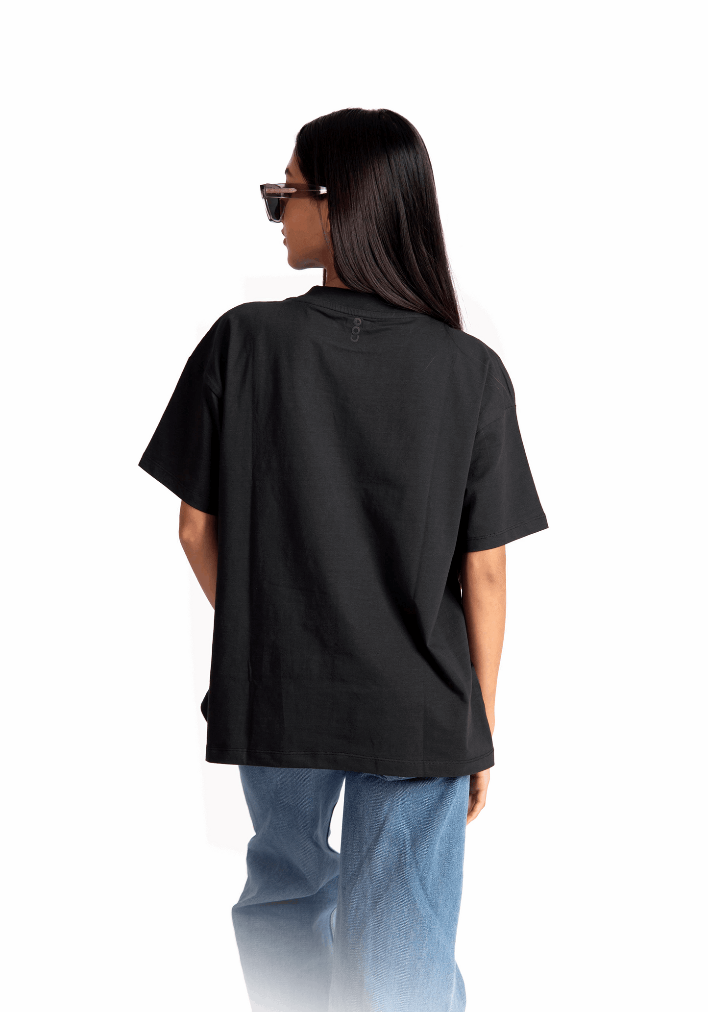 Stylera women's relaxed fit black tee shown from the back worn with blue jeans and sunglasses