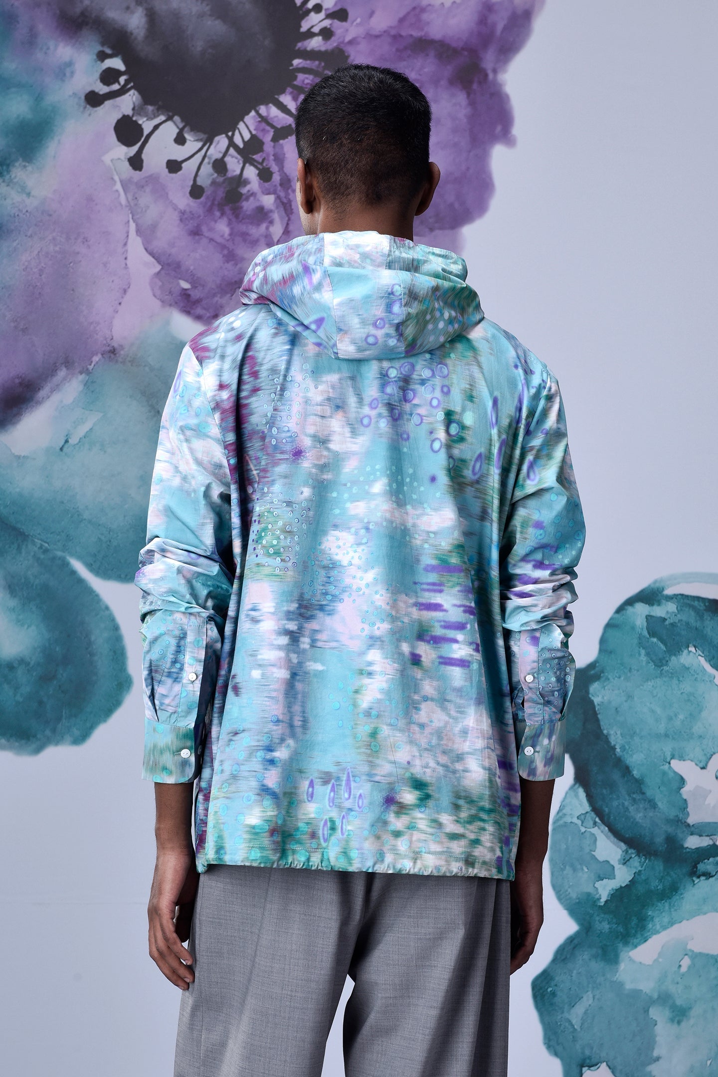 Back view of model wearing Stylera artistic print hoodie shirt in aqua purple watercolor