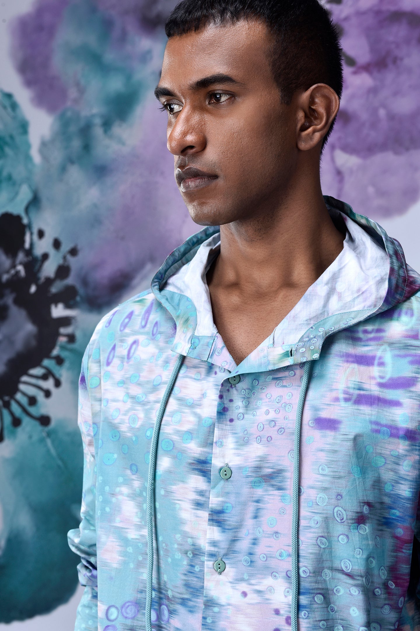 Stylera model wearing an artistic print hoodie shirt in pastel teal purple watercolor pattern
