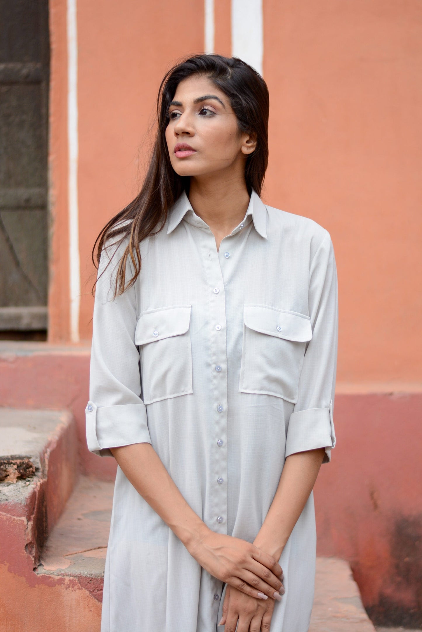 Model wearing an ash grey midi shirt dress with button-down closure and breast pockets