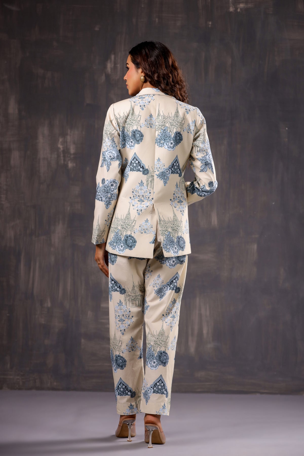 Rear view of woman in Stylera cream suit with blue floral motifs, blazer and trousers Floral print two piece set for ladies.