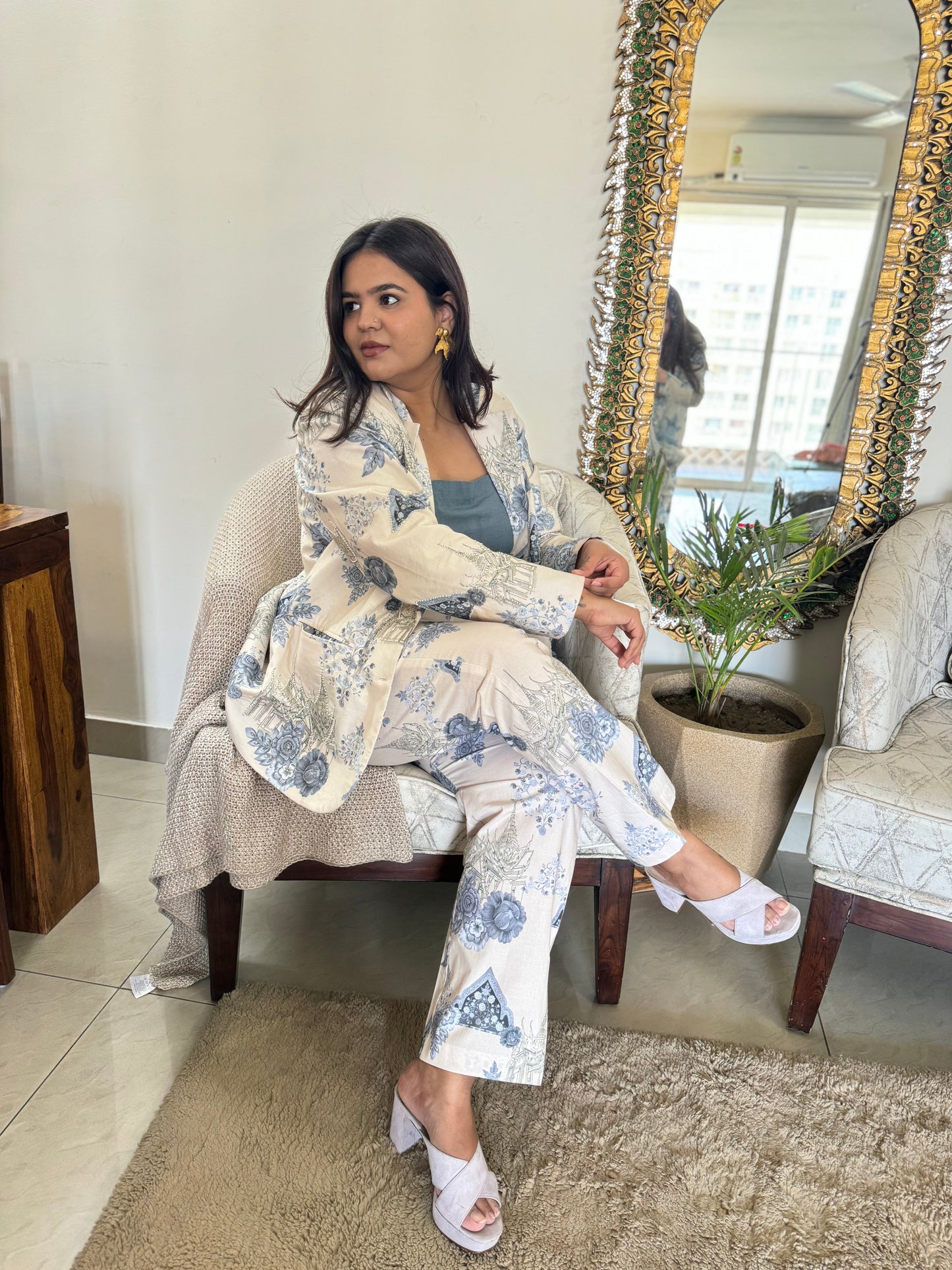 Woman seated wearing Stylera Floral print two piece set for ladies. cream blue blazer pant set with white sandals