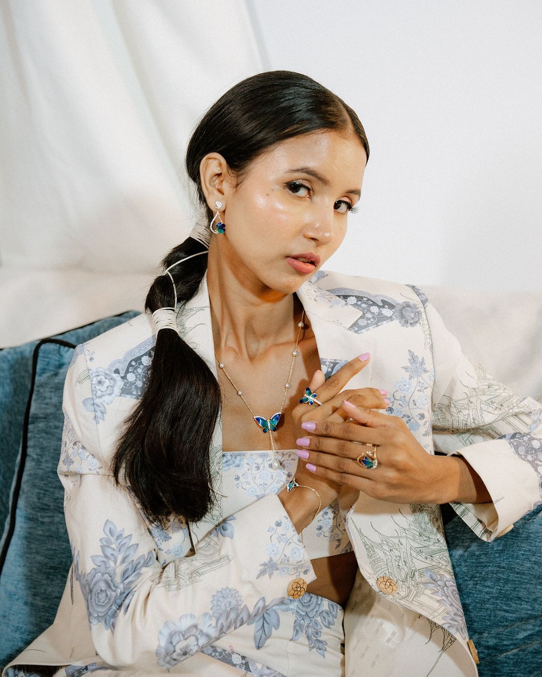 Model seated wearing a Stylera floral blazer and crop top Floral print two piece set for ladies with butterfly jewelry