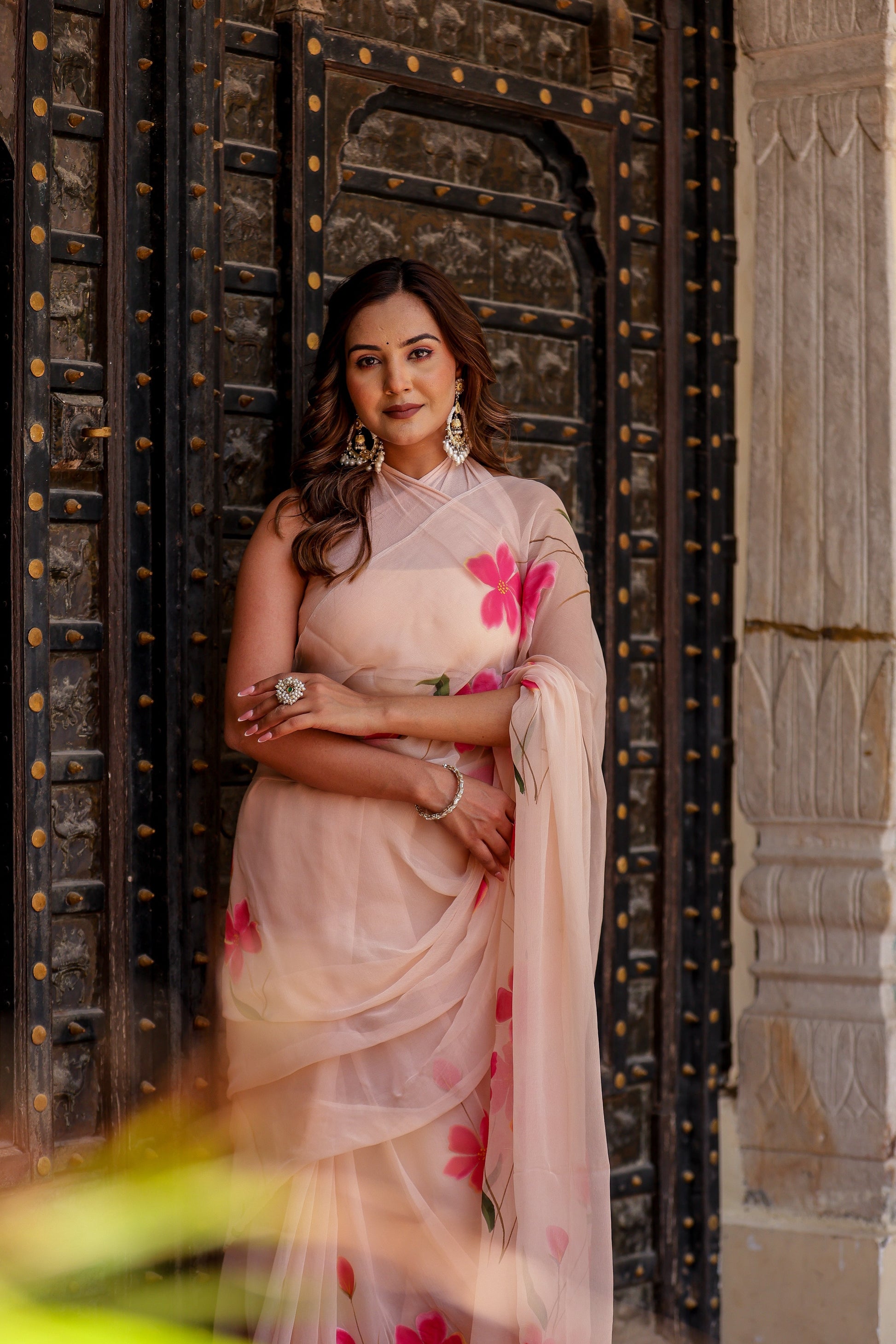 Elegant beige floral chiffon saree featuring vibrant pink flowers and intricate draping style