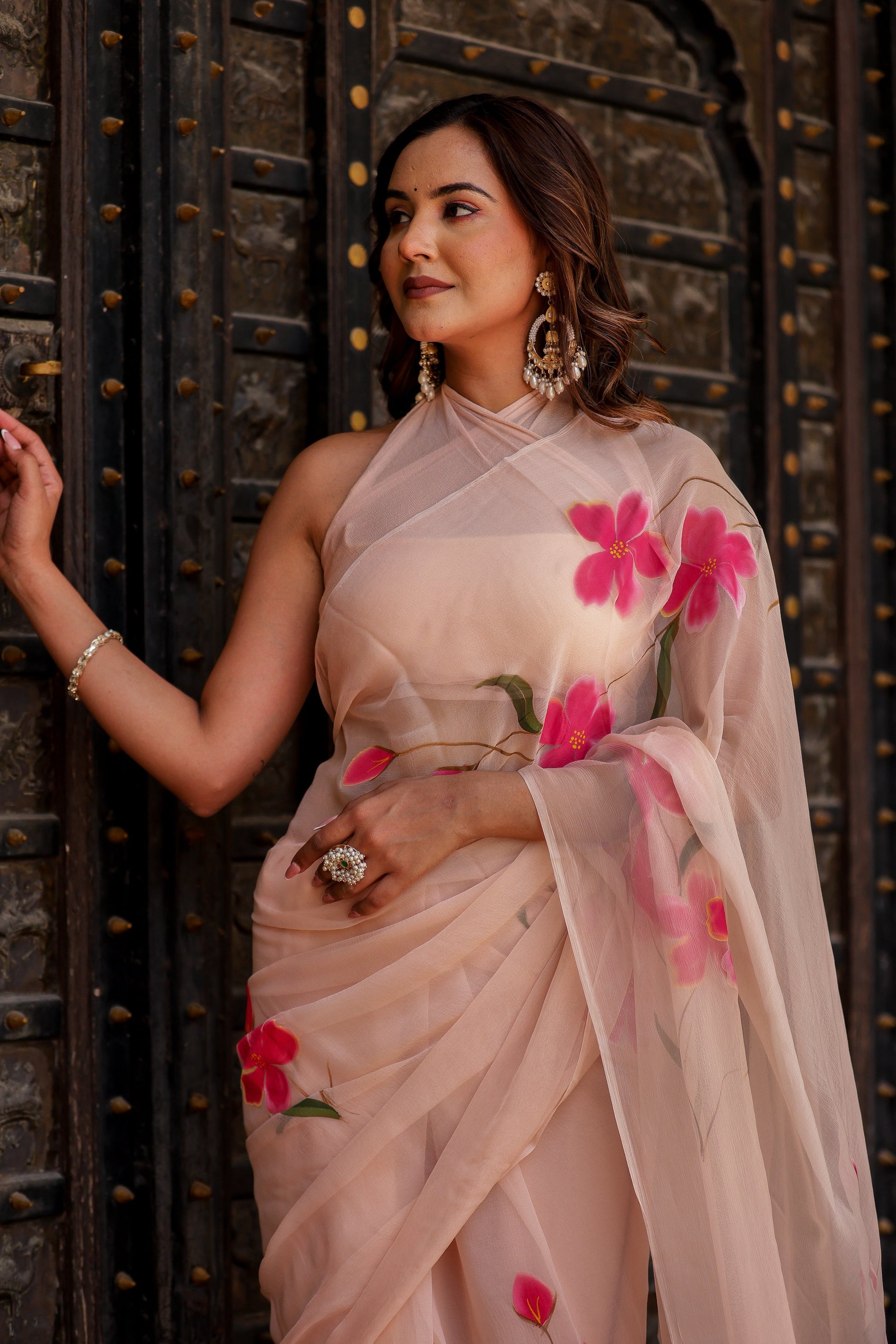 Elegant beige floral chiffon saree with vibrant pink flowers, perfect for festive occasions