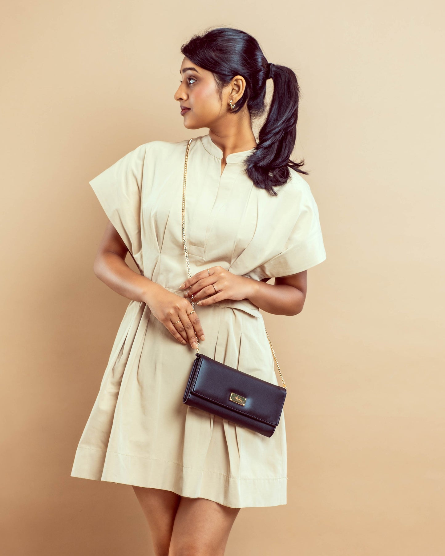 Stylish black sling wallet purse worn crossbody on a model in a beige dress