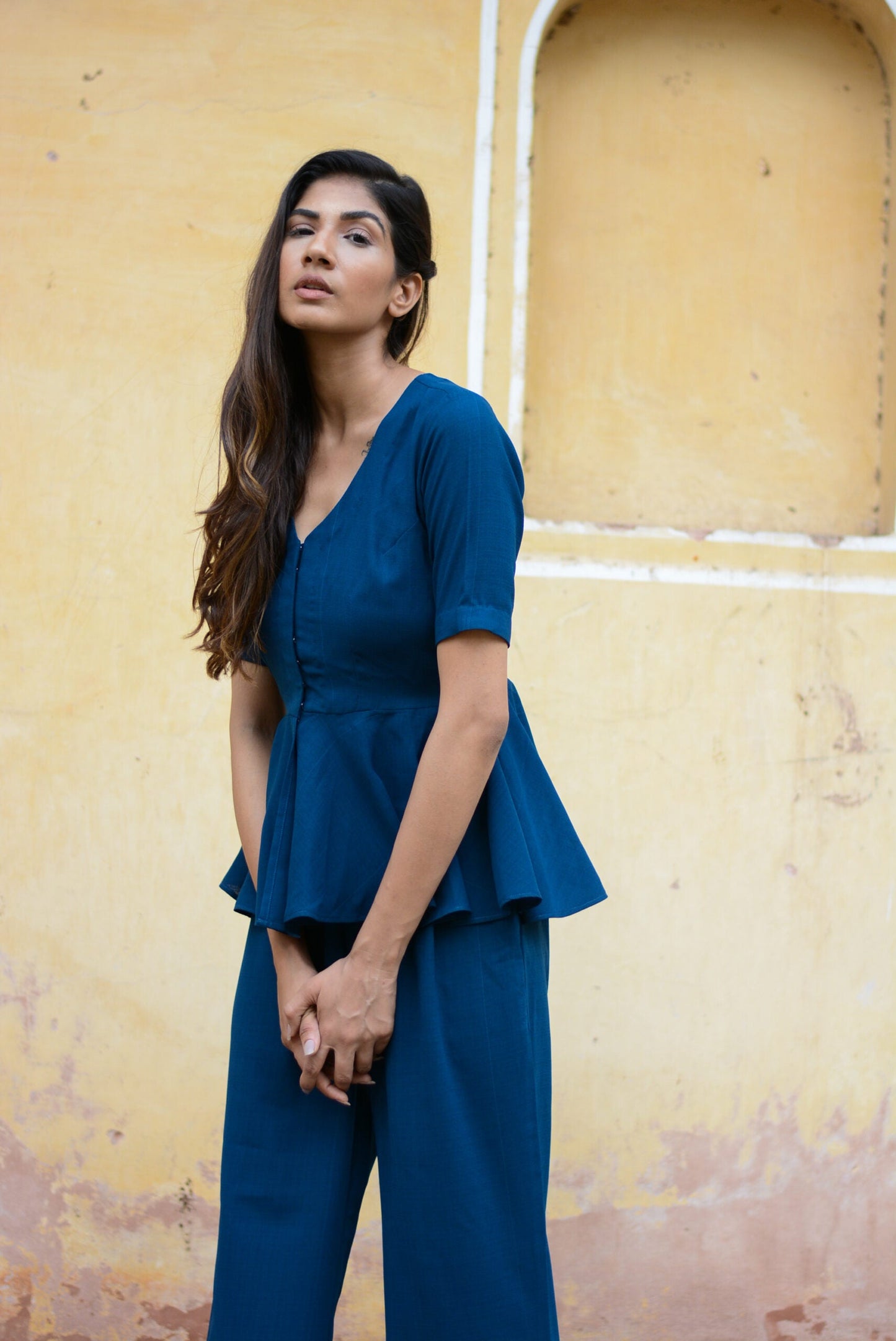 Model wearing a Yale blue peplum co-ord set with a stylish peplum top and matching trousers