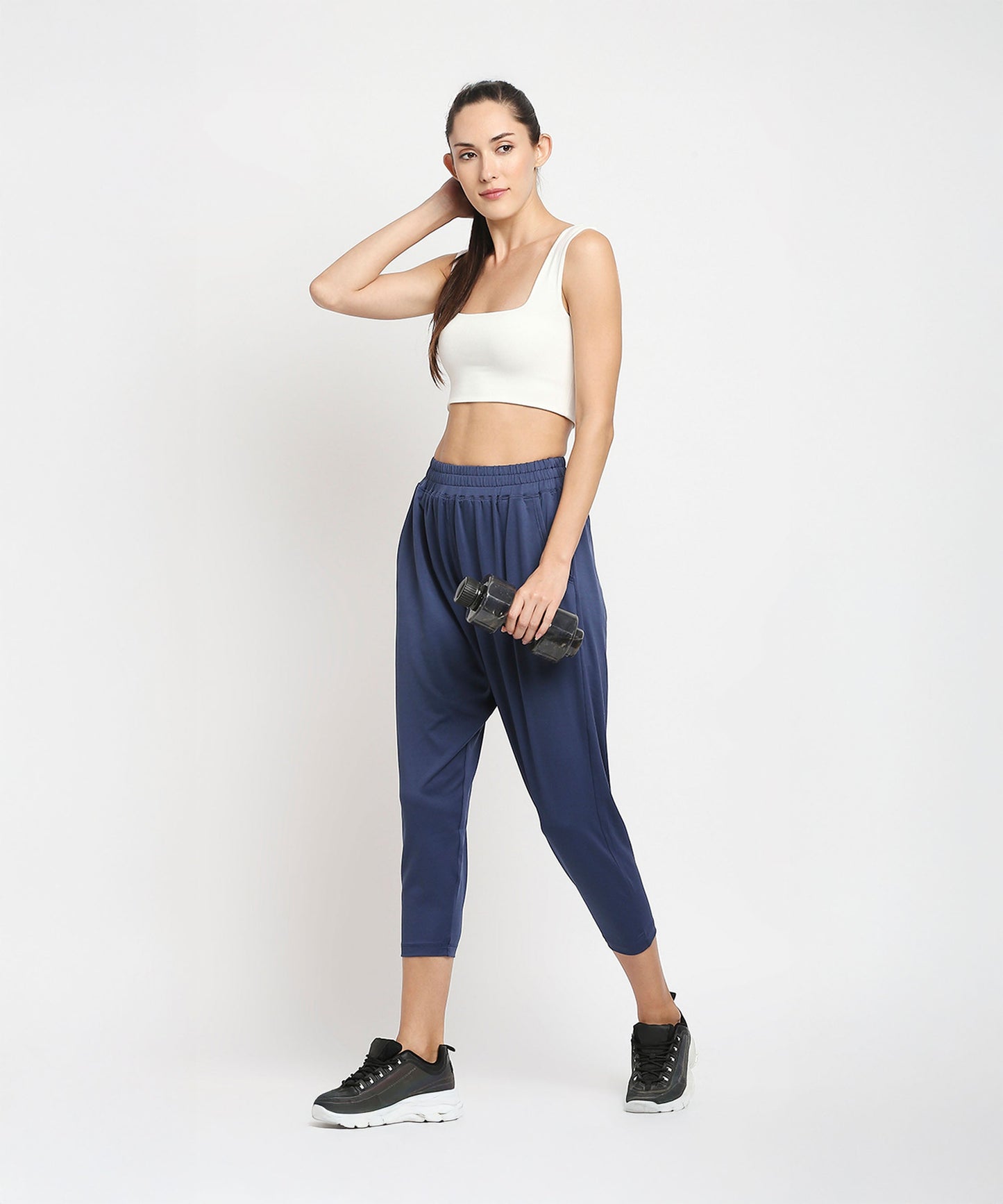Model wearing blue yoga pants for women with a white crop top and sporty shoes