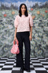Stylera model wearing a pink lace casual semi fit top for women with puff sleeves and black trousers