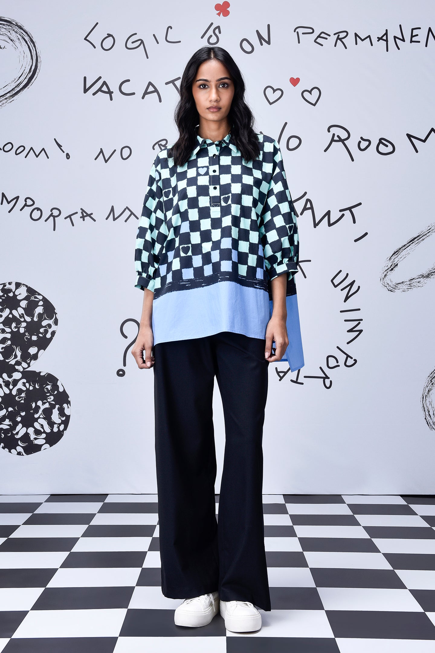 Stylera chess board print oversized shirt on model with layered blue hem and wide black trousers