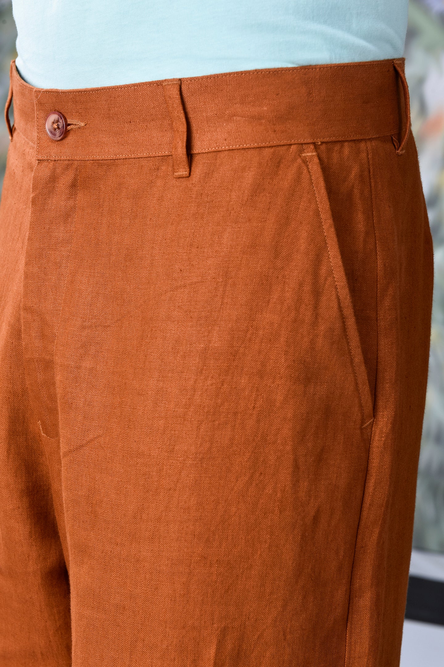 Close-up of dark camel linen trousers by Stylera featuring a buttoned waistband and side pocket