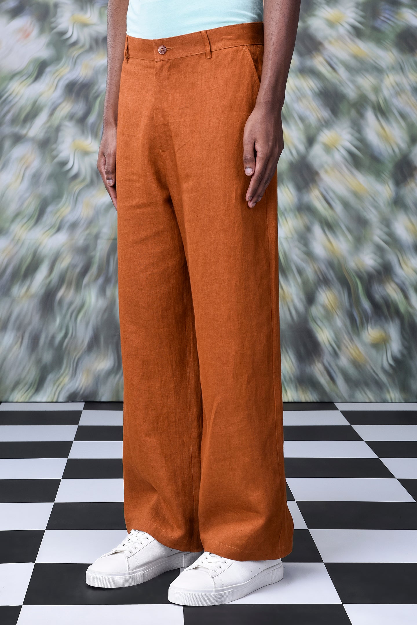 Dark camel linen trousers from Stylera worn with white sneakers on checkered floor