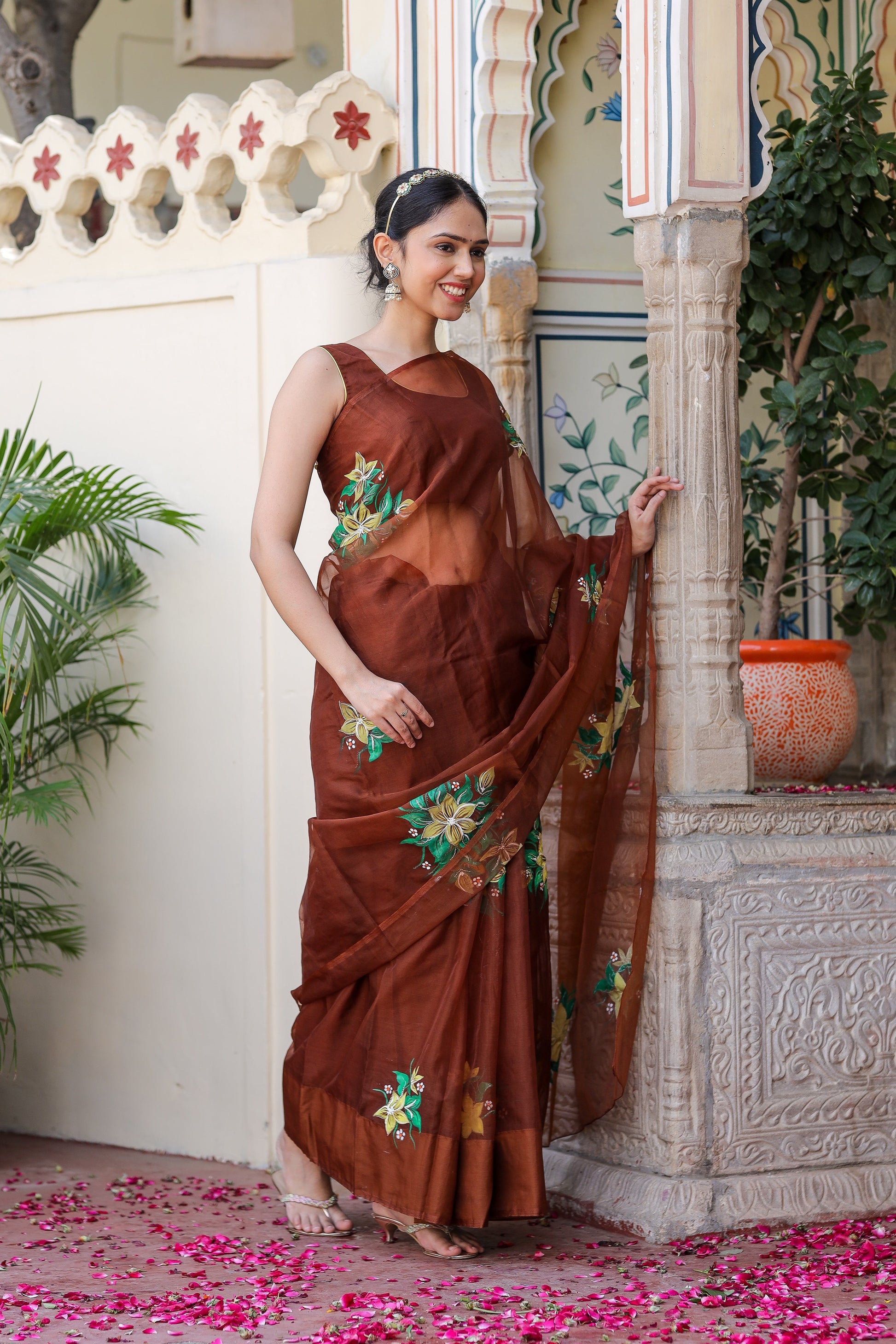 Elegant designer brown saree for wedding featuring floral embroidery, worn by a model in a festive setting