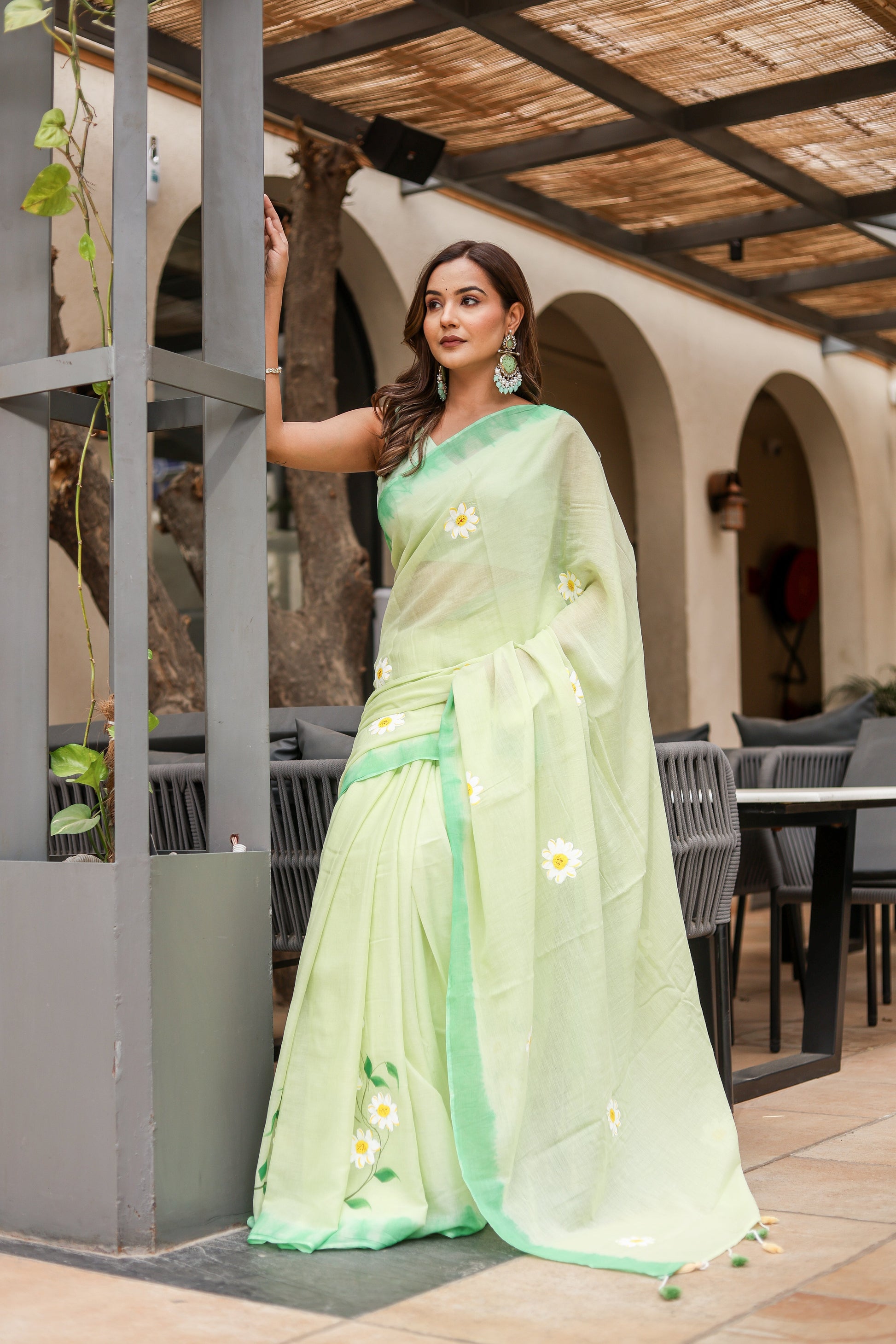 Elegant designer malmal saree with flowers in soft green, paired with matching accessories for a stylish look