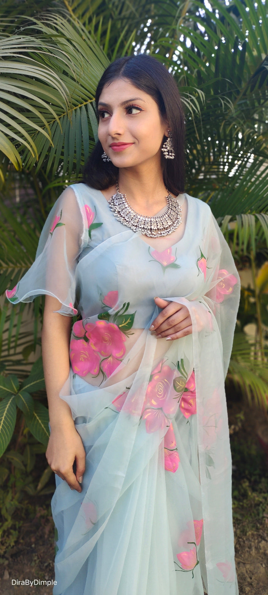 Designer party wear organza saree in light blue with floral prints, styled elegantly for festive occasions