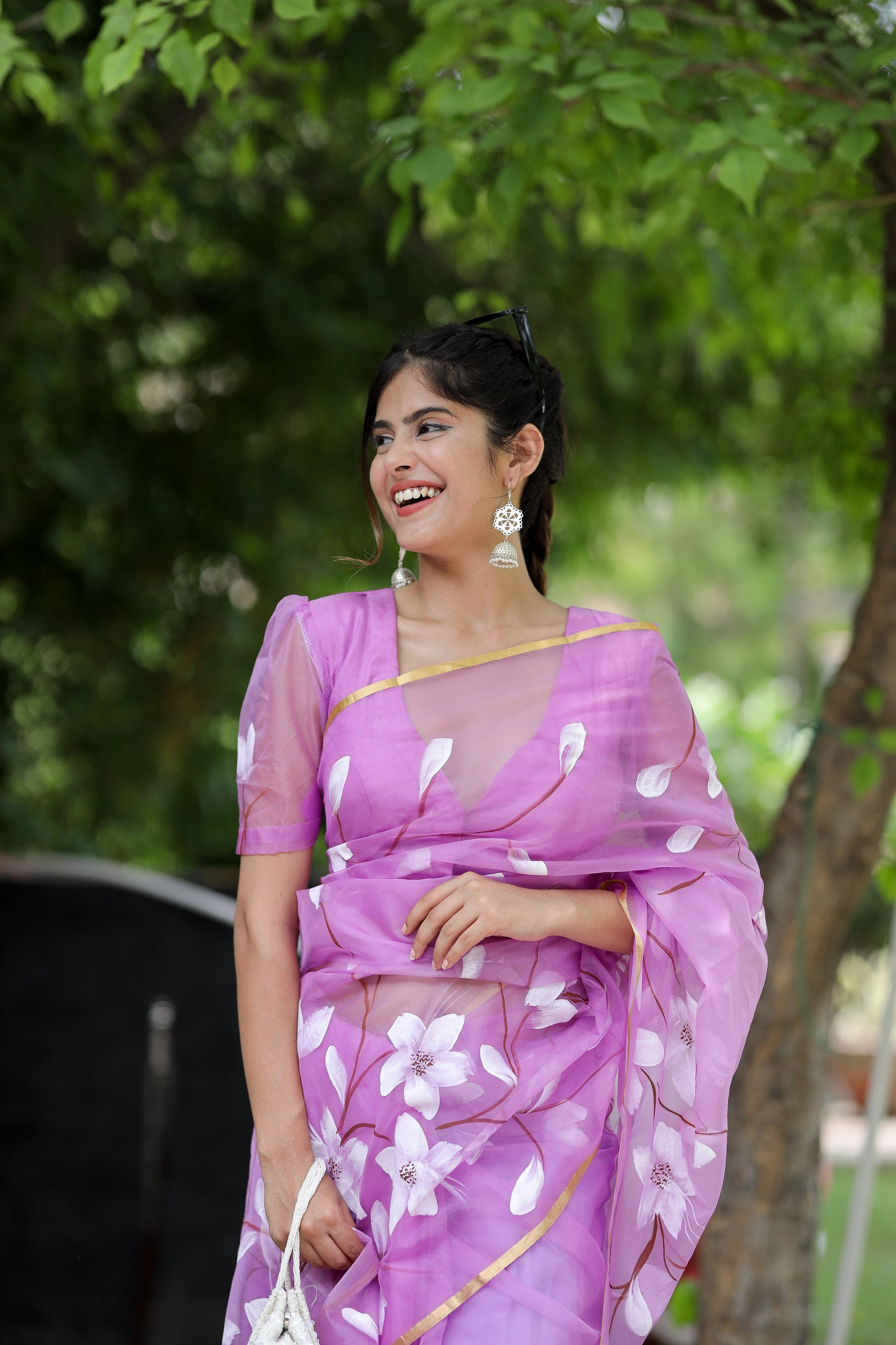 Elegant designer saree for special occasions in purple with floral patterns, paired with matching earrings