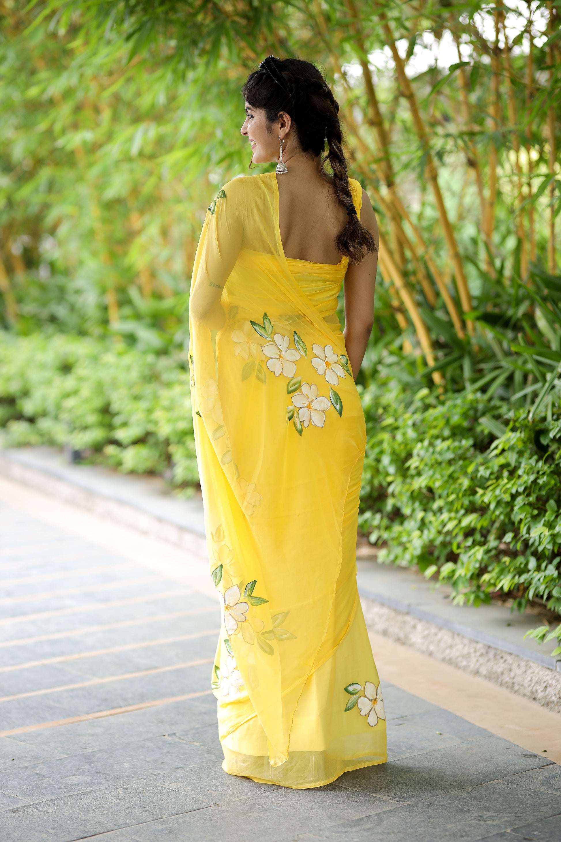 Elegant yellow designer saree with floral art, featuring a graceful drape and intricate embroidery