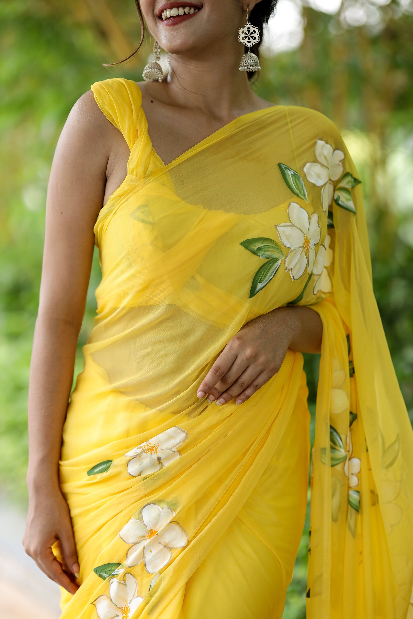 Bright yellow designer saree with floral art featuring elegant white blossoms and green leaves
