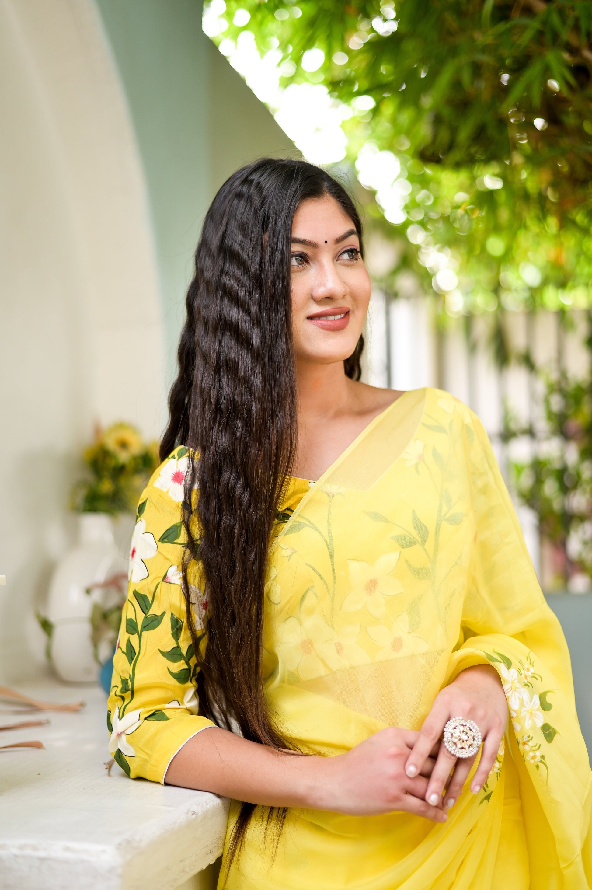 Model wearing a designer yellow saree hand painted with floral patterns, showcasing elegance and style