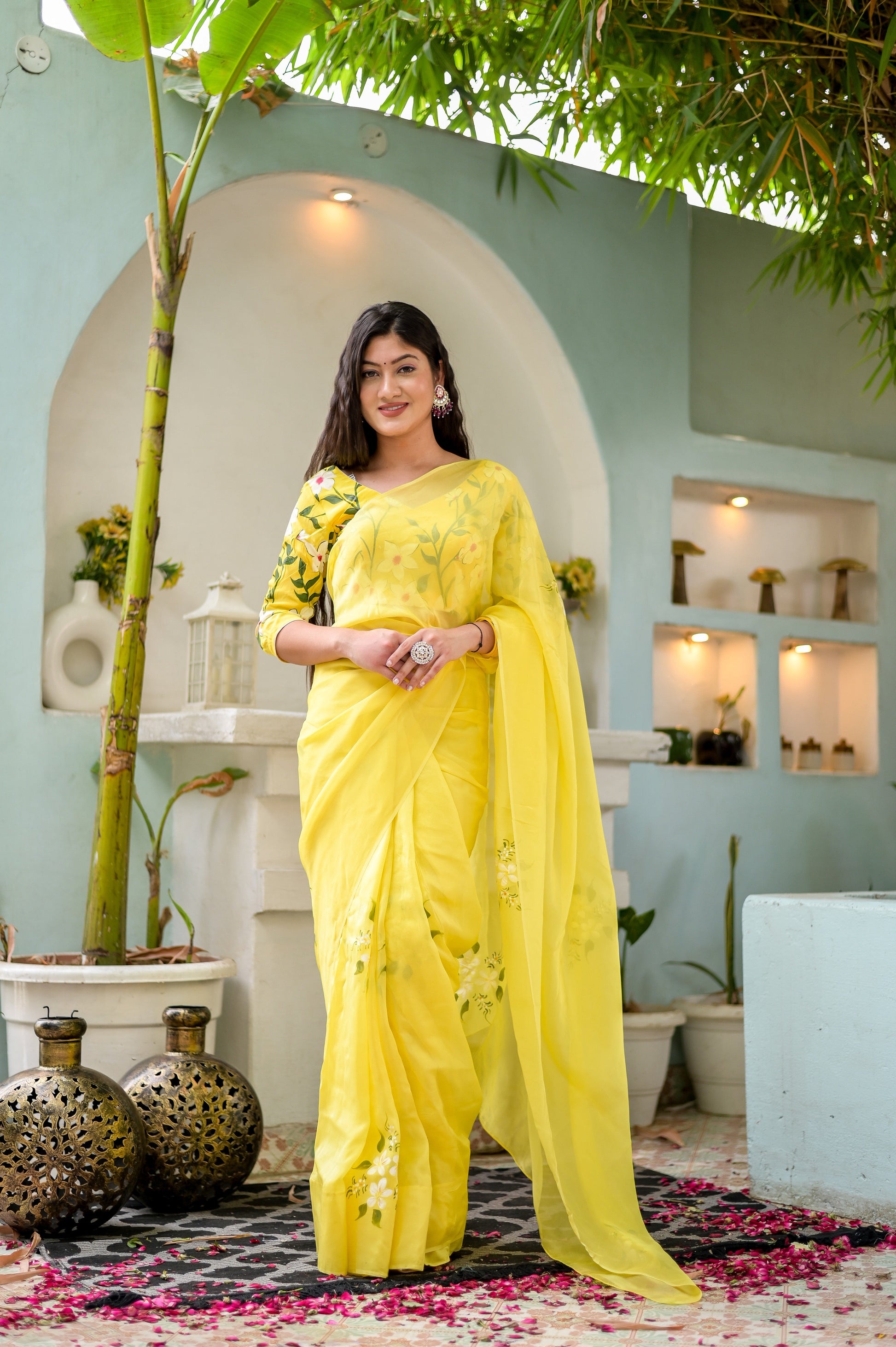 Elegant designer yellow saree hand painted with floral designs, worn by a model in a beautiful setting