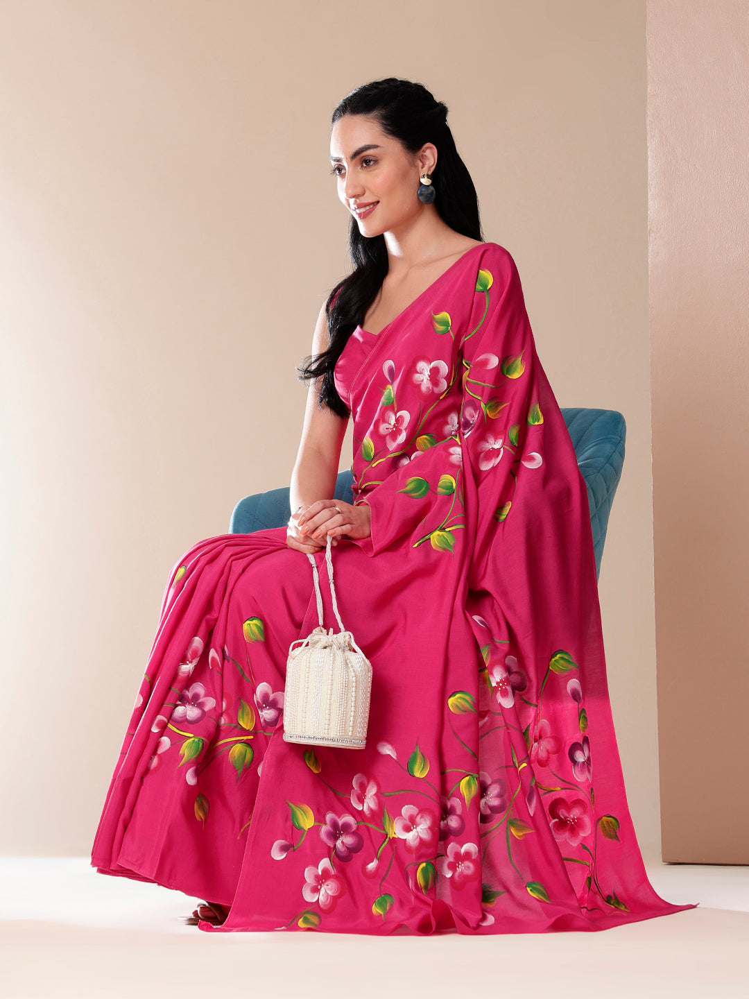 Elegant pink saree for parties with floral designs, paired with a stylish bag and earrings