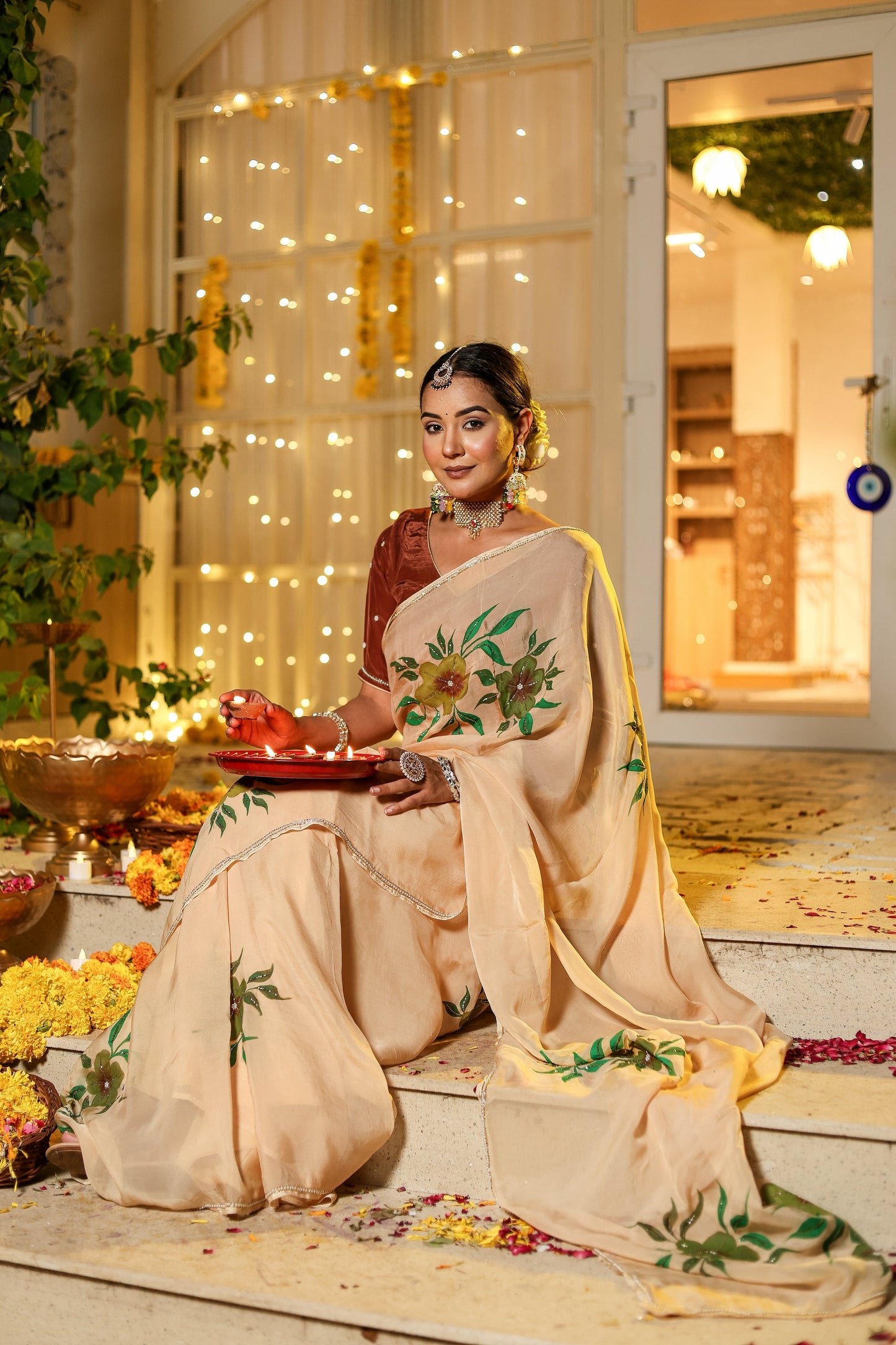 Elegant woman wearing an exclusive handmade Indian saree adorned with floral designs, seated gracefully outdoors
