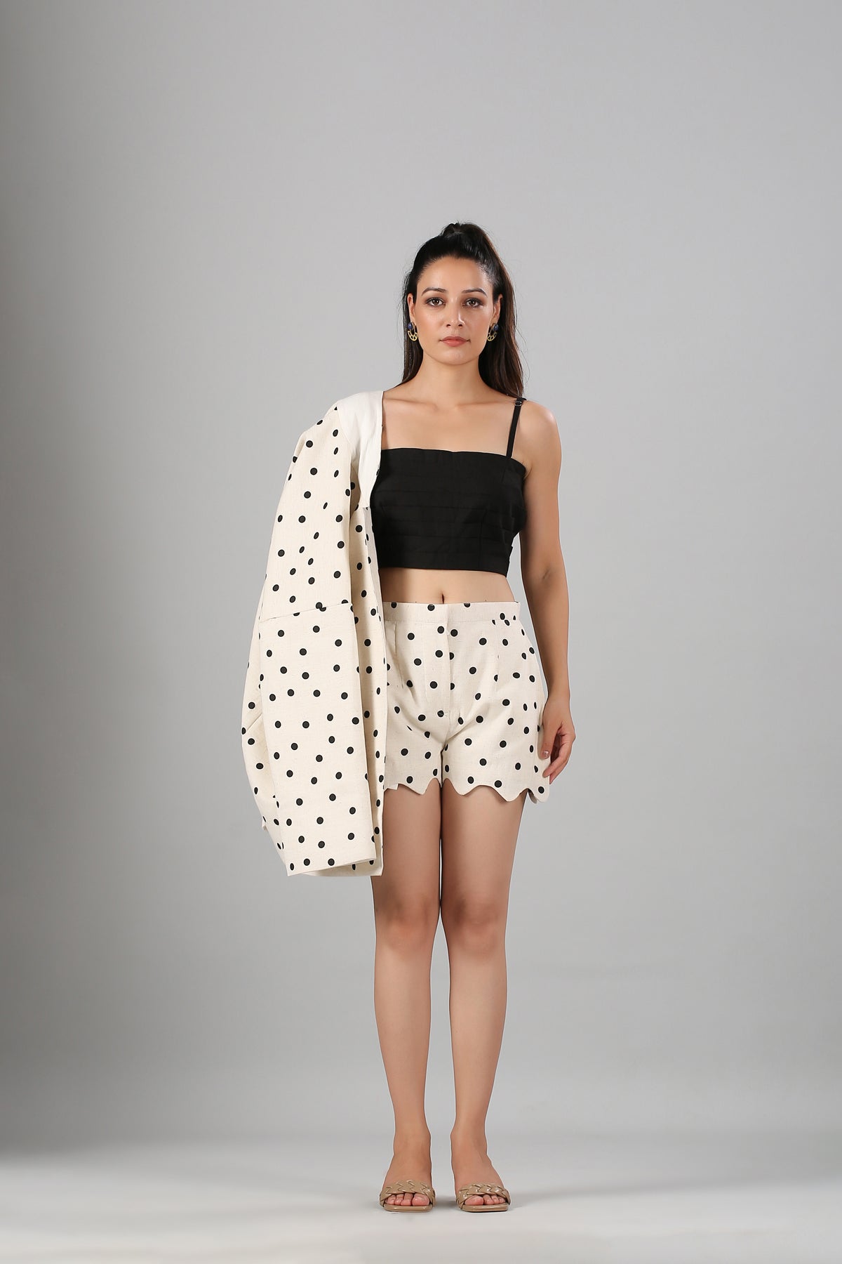 Model wearing fashionable two piece suit for ladies cream polka dot blazer on shoulder with scalloped shorts and black crop top
