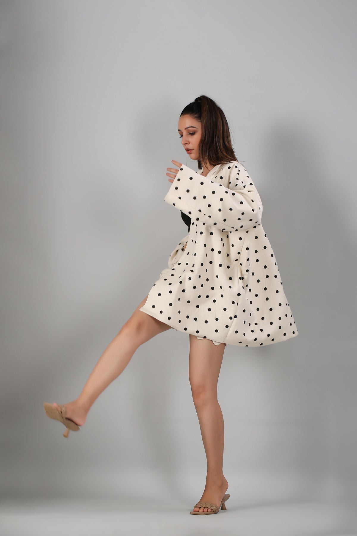 Model wearing Stylera fashionable two piece suit for ladies in cream polka dot oversized blazer and matching mini skirt posing in heels