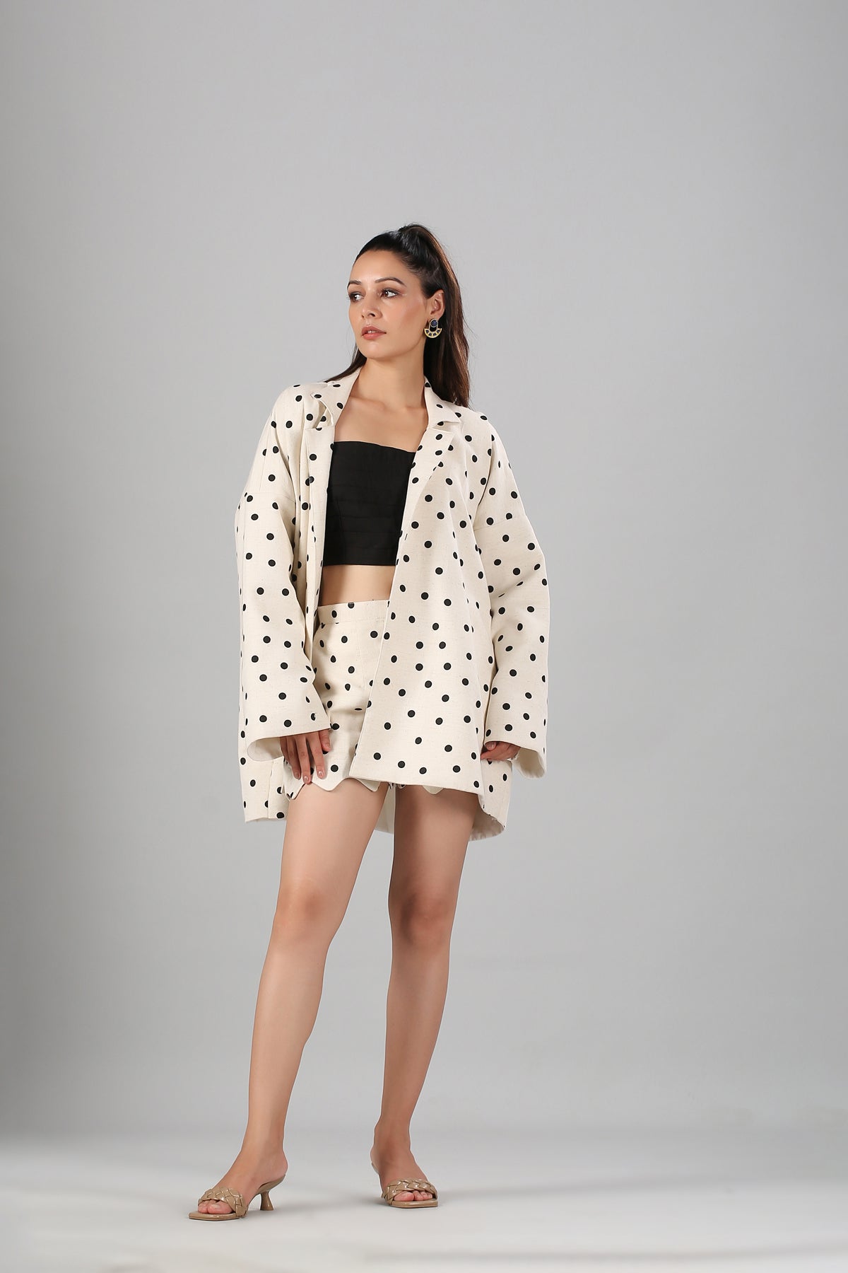 Model wearing Stylera fashionable two piece suit for ladies cream polka dot blazer and matching shorts with black bandeau and heels