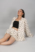 Woman reclining in cream polka dot matching shirt and shorts with black crop top fashionable two piece suit for ladies