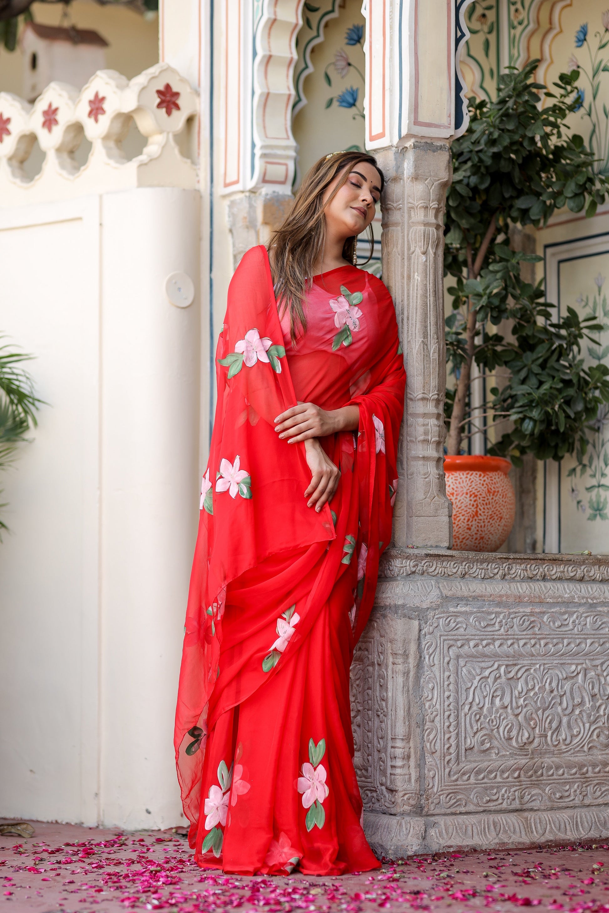 Model wearing a floral designer chiffon saree in red with vibrant floral embroidery for festive occasions