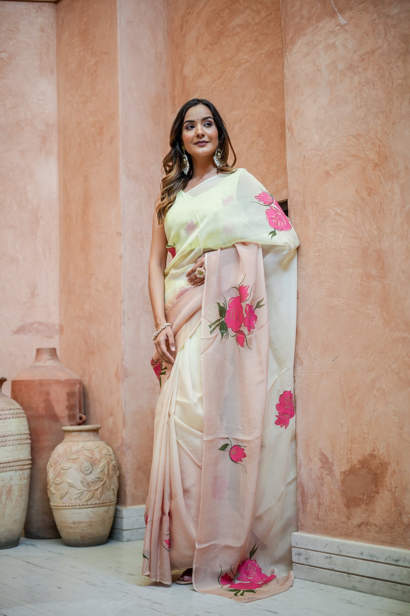 Stylera Graceful Tints floral saree in soft peach with vibrant rose prints, styled elegantly on a model