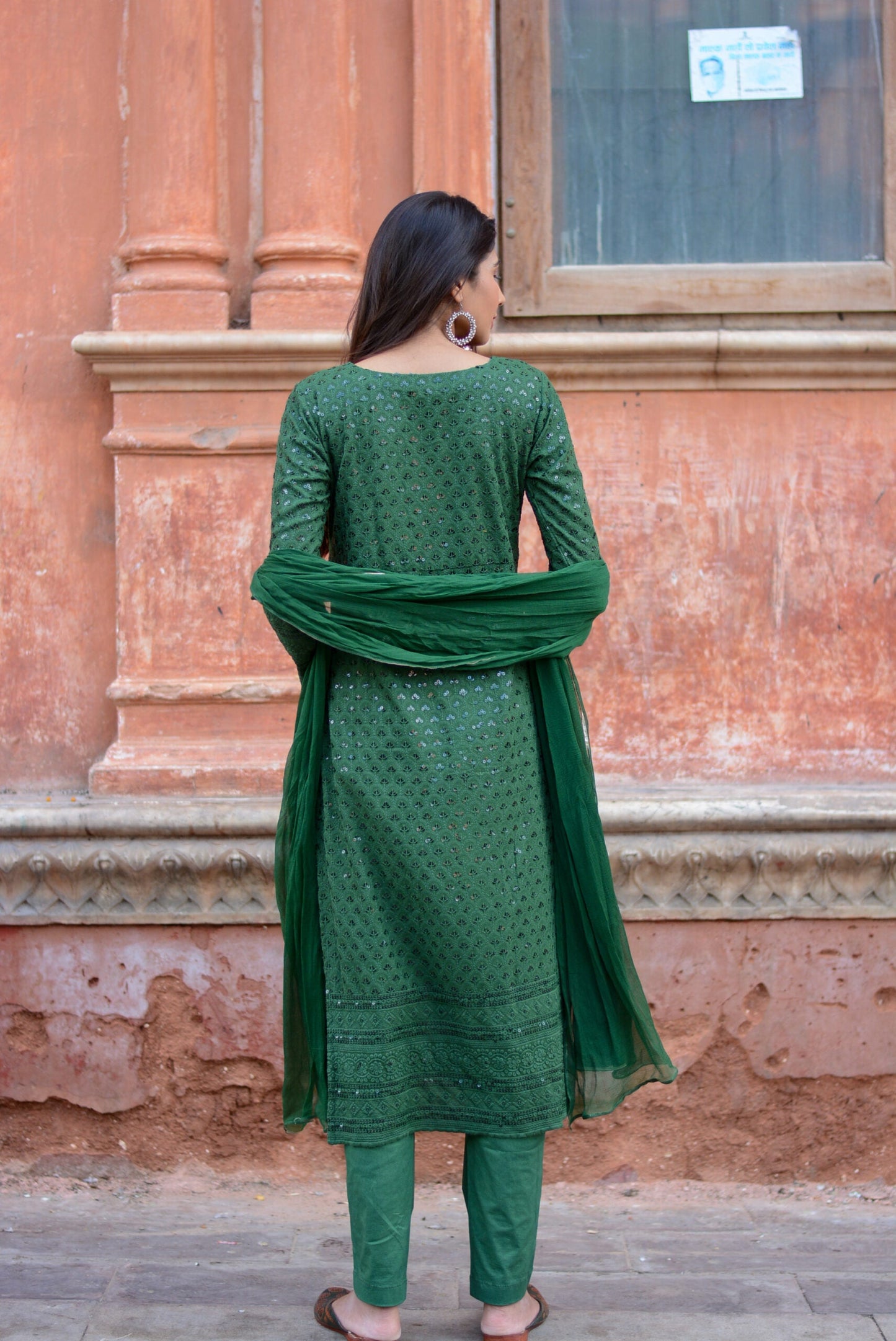 Back view of woman wearing a green three piece suit for women with detailed embroidery and matching dupatta
