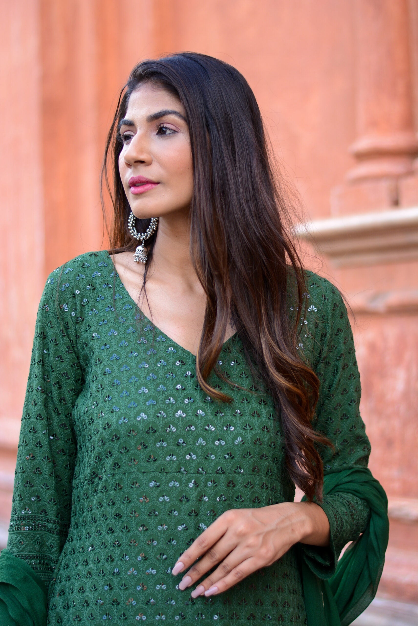 Woman wearing a green three piece suit for women with intricate embroidery by Stylera