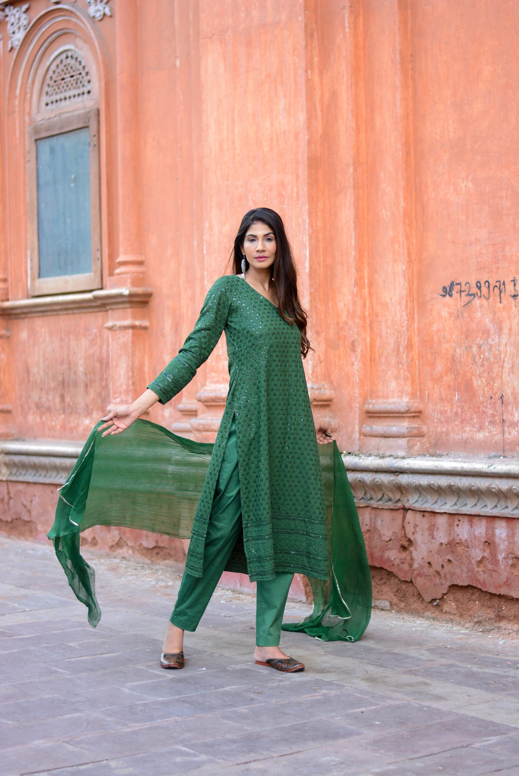 Woman wearing green three piece suit for women standing outdoors with matching dupatta and pants
