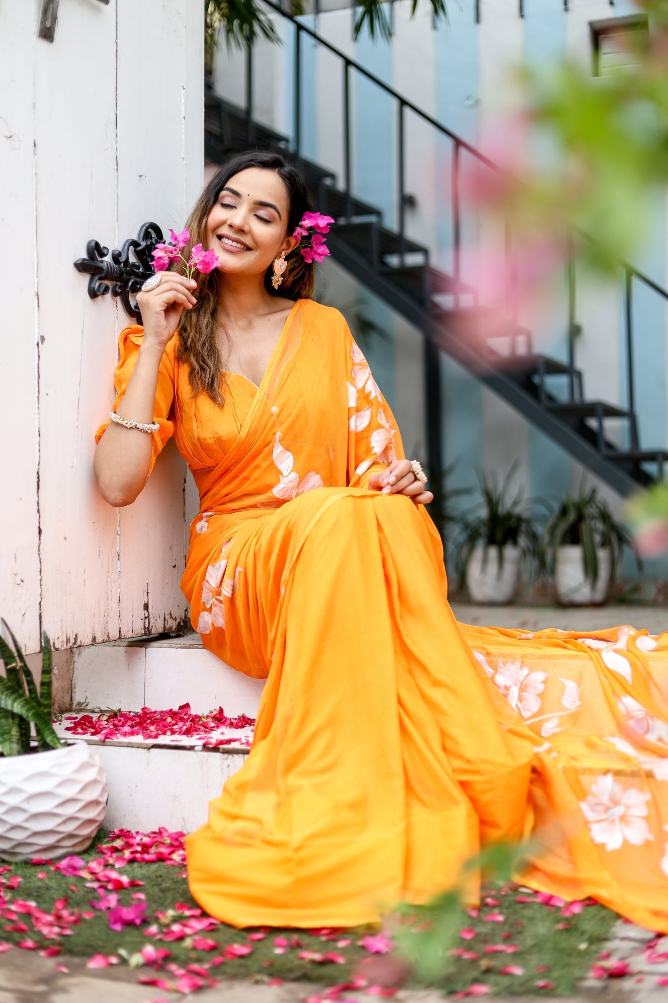 Elegant model wearing a handpainted chiffon saree in vibrant orange with floral designs for festive occasions