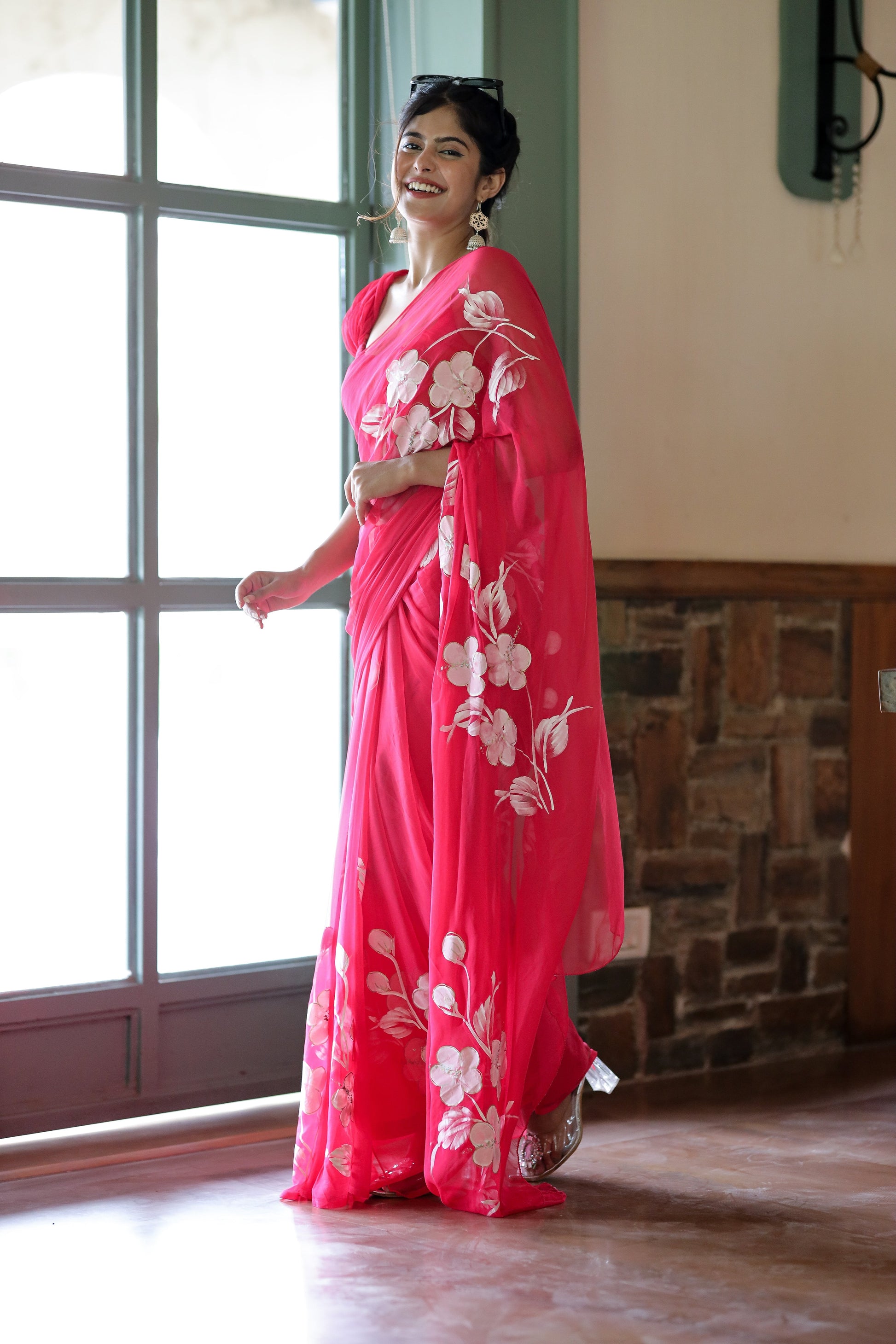 Elegant model wearing a handpainted chiffon saree rani pink with floral designs, showcasing grace and style.