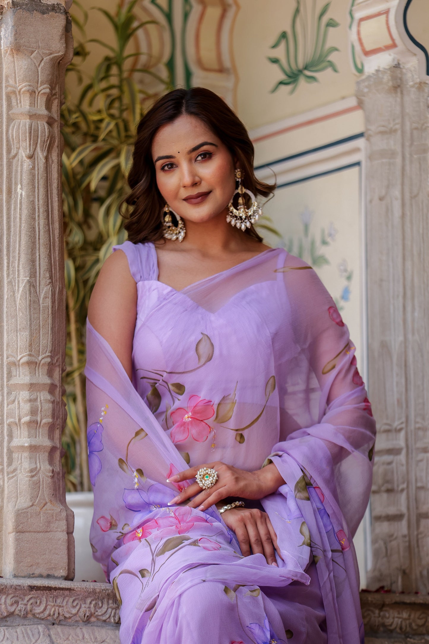 Elegant model wearing a handpainted lavender chiffon saree with floral designs and matching accessories