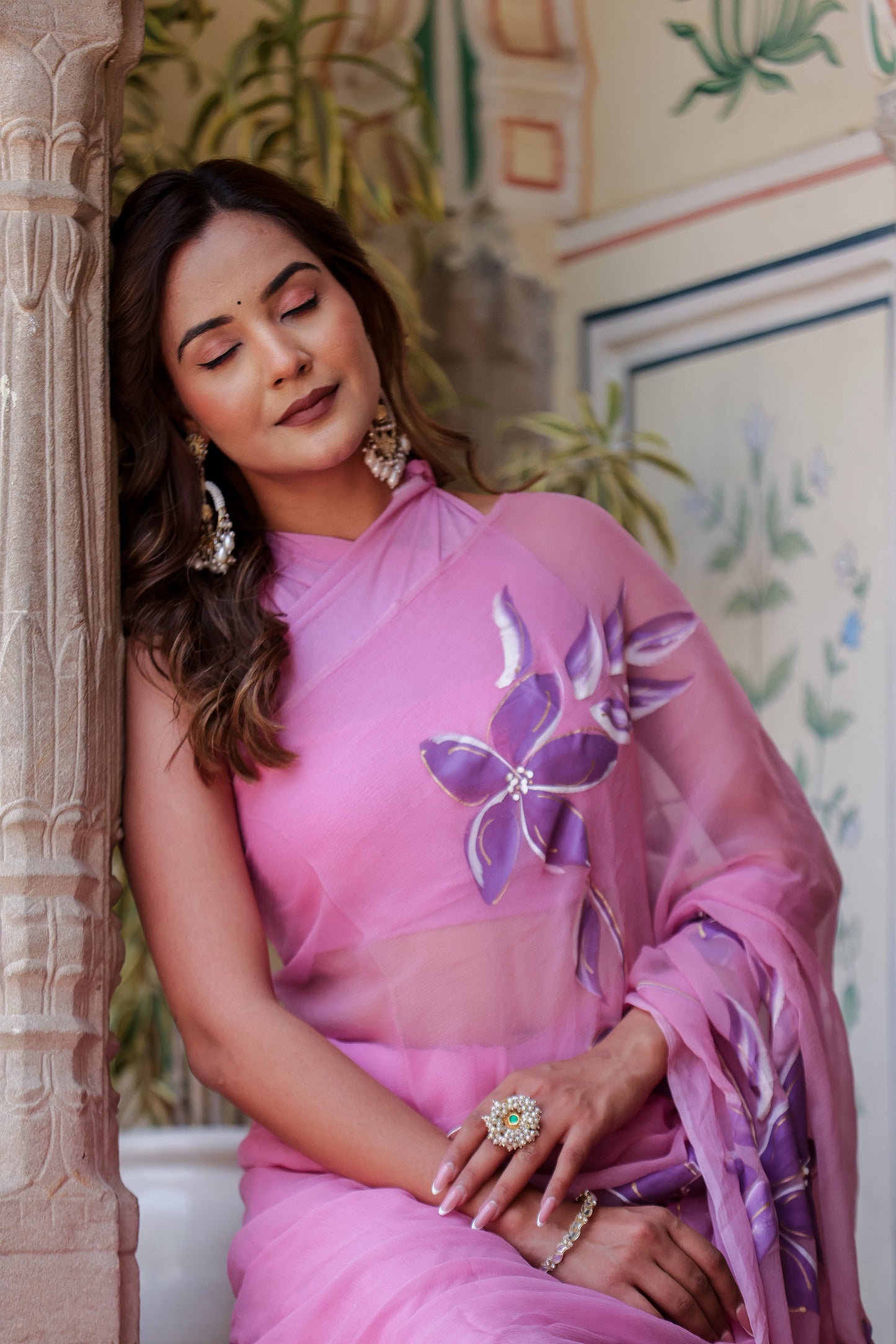 Elegant handpainted lavender chiffon saree with floral designs, worn by a model in a serene setting