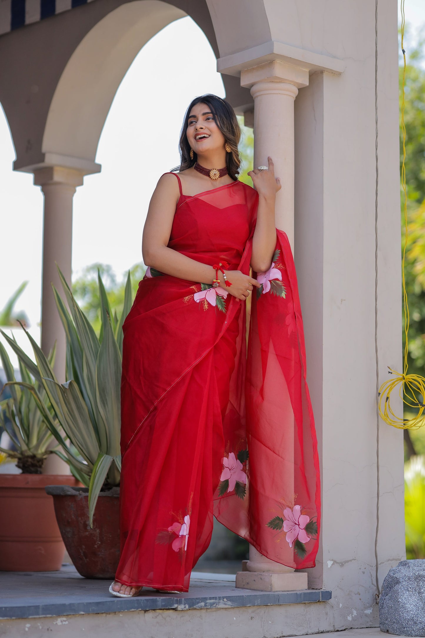 Elegant handpainted red organza saree adorned with floral motifs, perfect for festive occasions