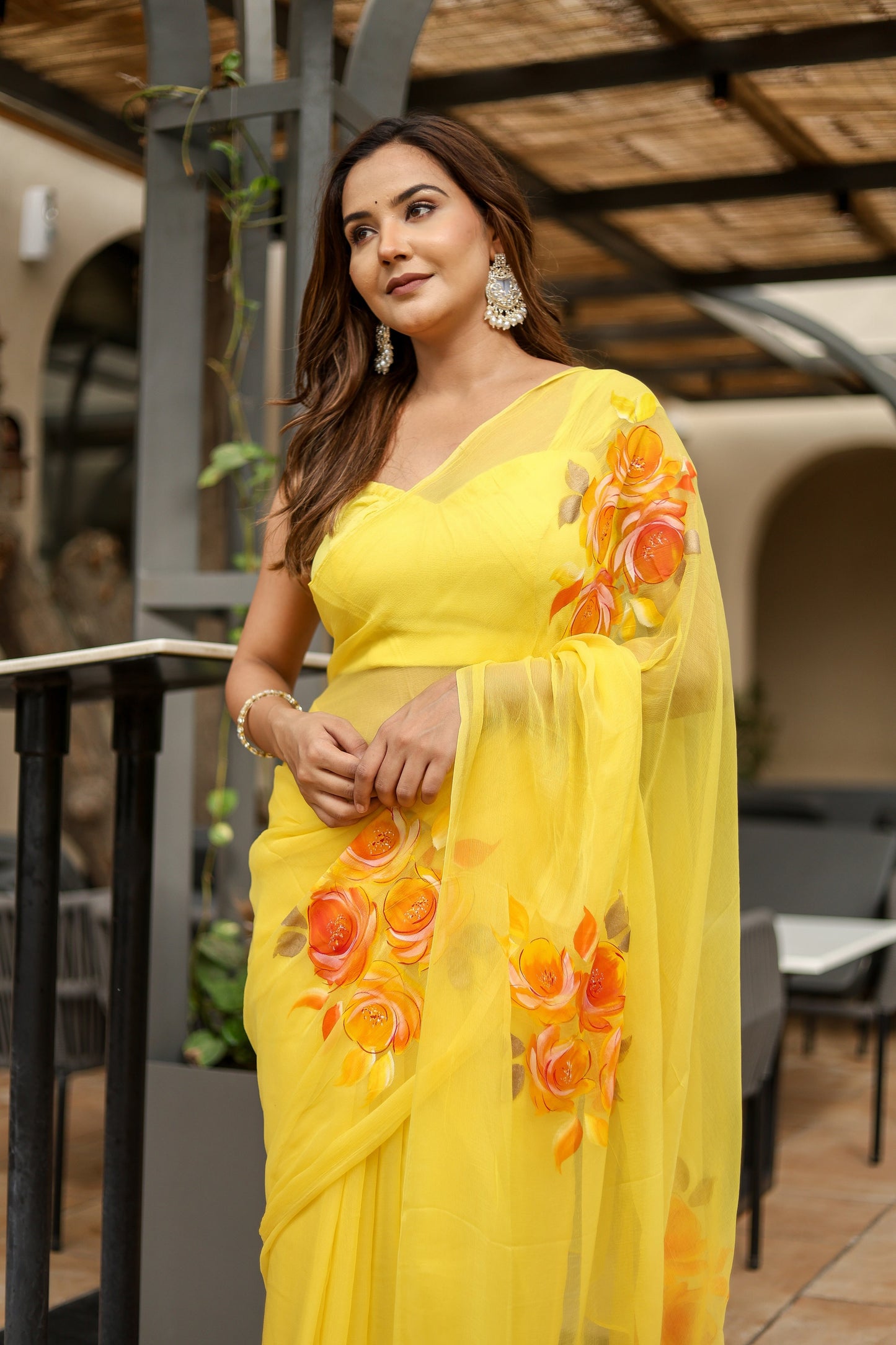 Elegant handpainted yellow chiffon saree adorned with floral designs, perfect for festive occasions