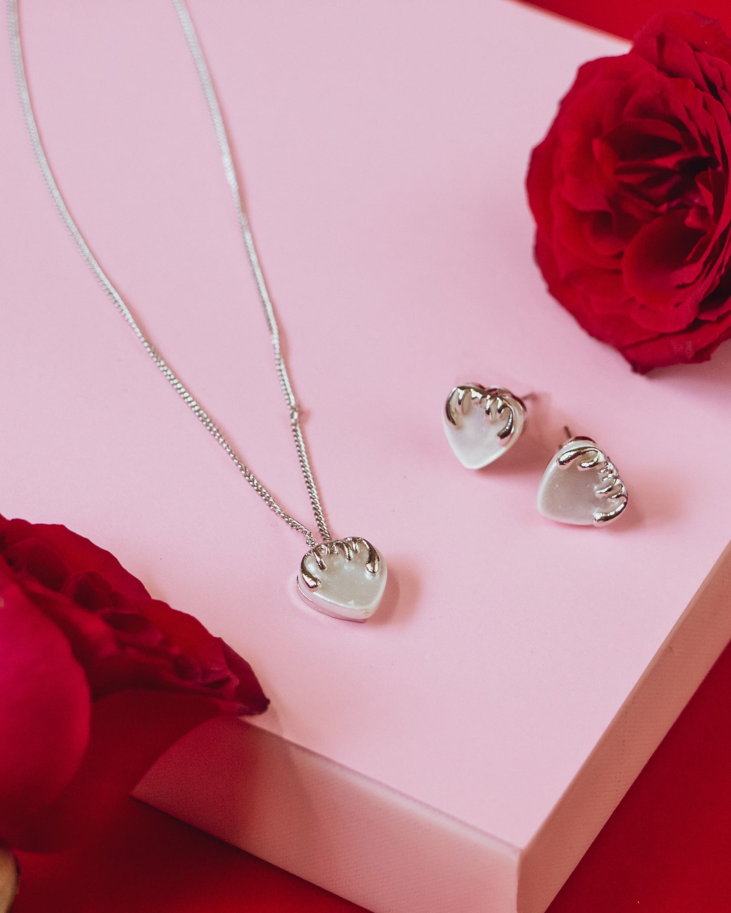 Stylera silver heart necklace with matching heart stud earrings on pink gift box with red roses