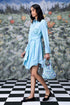 Model wearing Stylera blue green stripe dress with waist tie carrying floral handbag on checkerboard floor