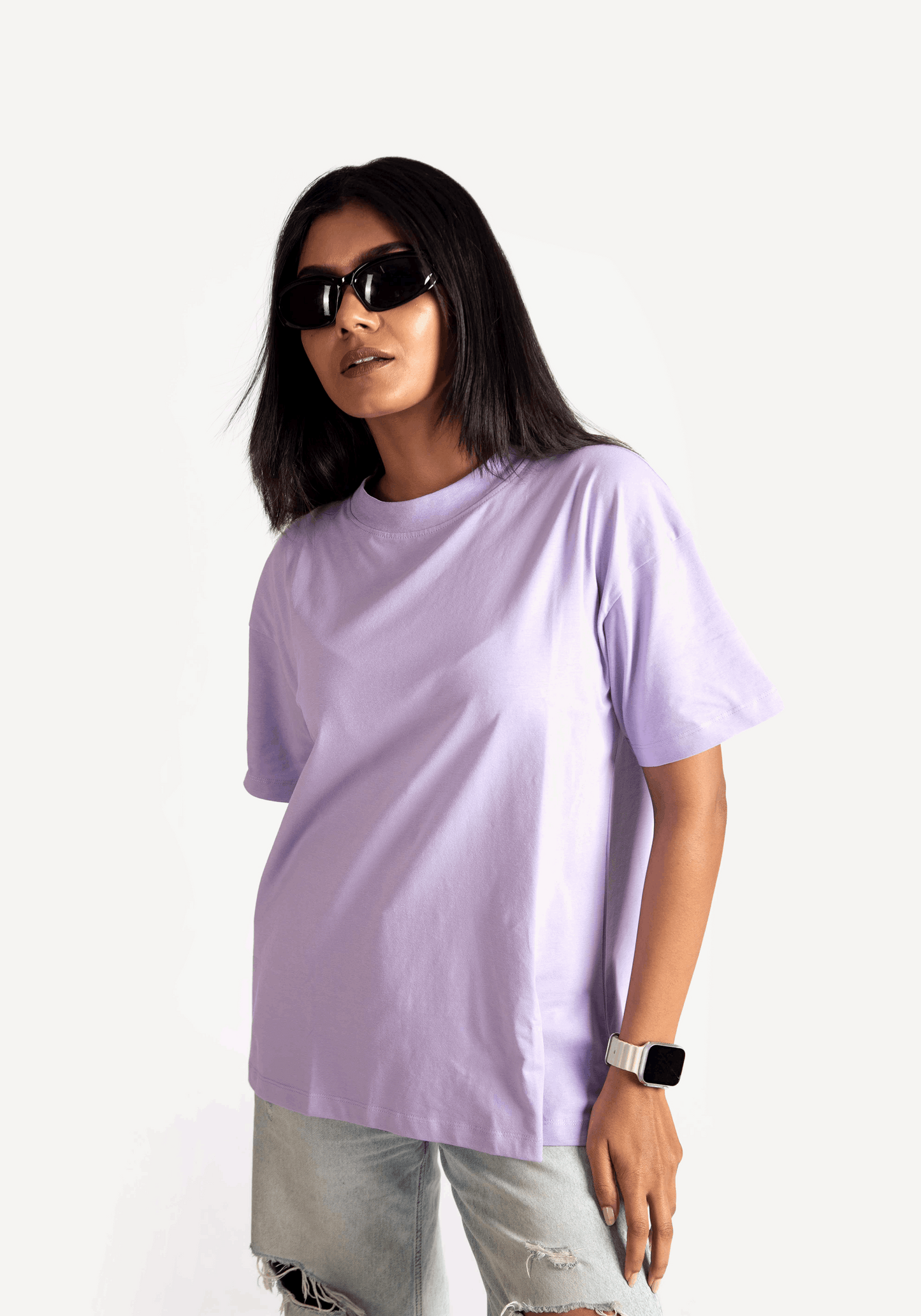 Woman wearing lavender oversized t-shirt with short sleeves paired with ripped jeans and black sunglasses