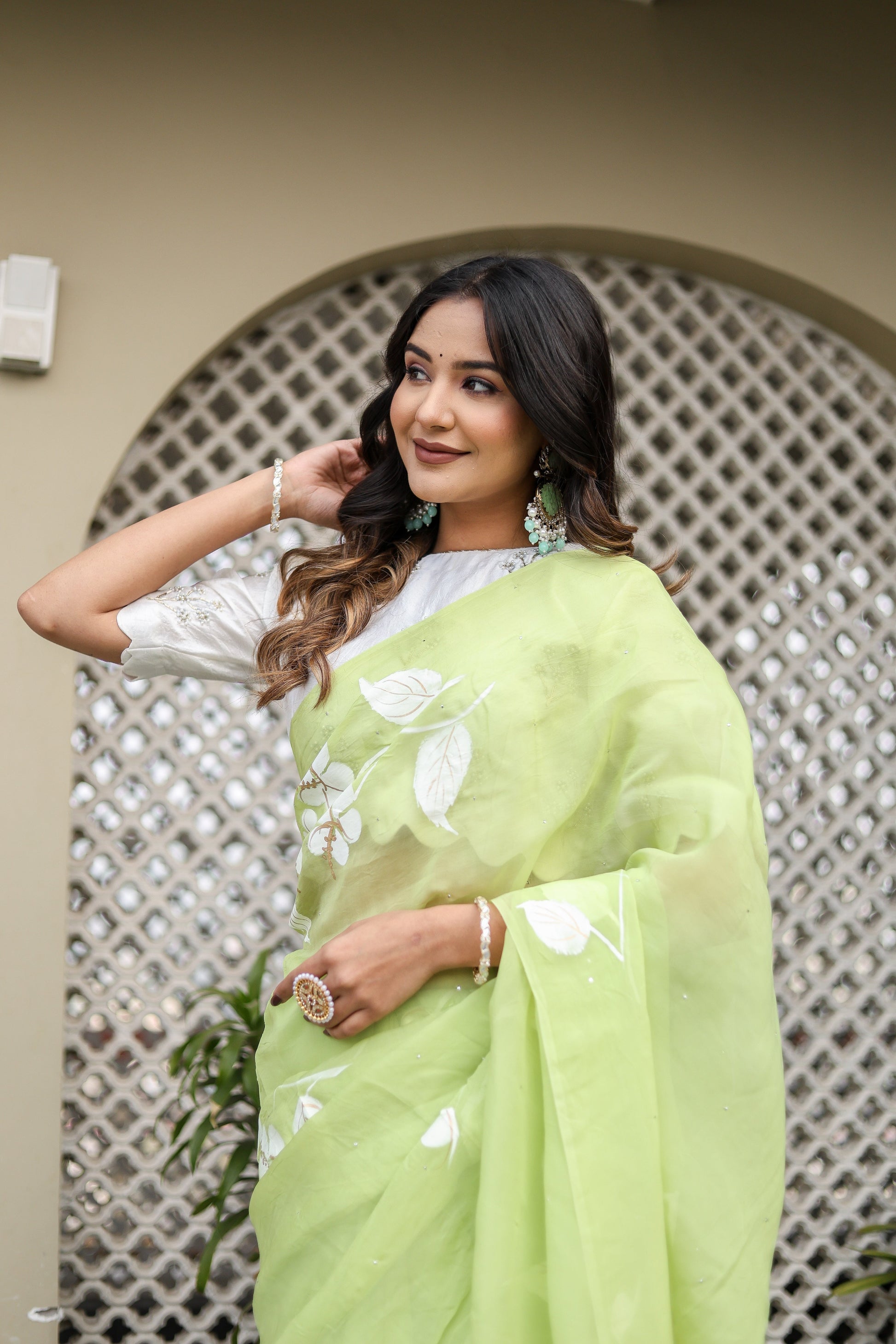 Lightweight party wear saree in green with floral designs, styled elegantly for a festive look