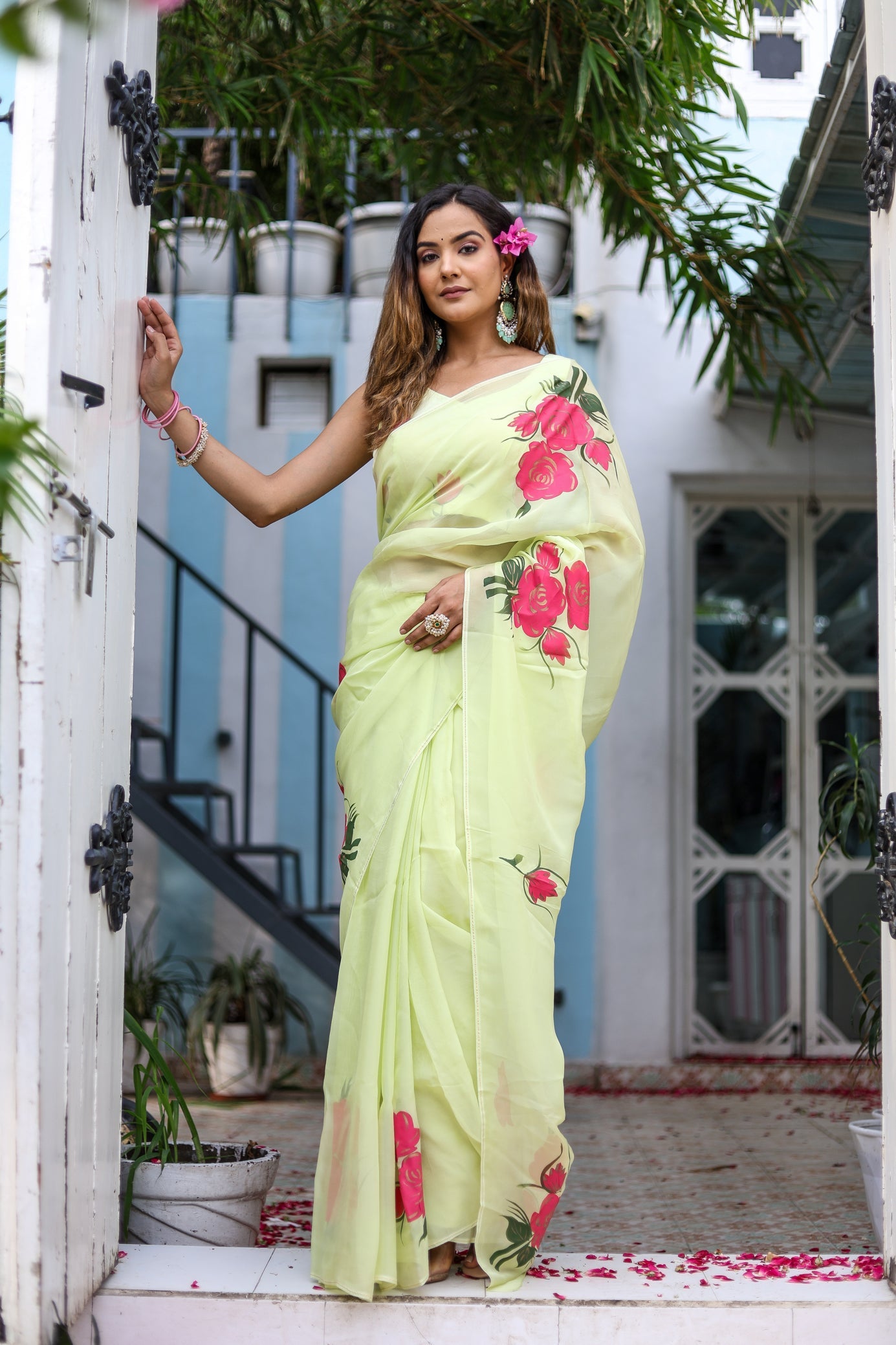 Model wearing a lightweight pastel saree with floral print, featuring vibrant pink flowers on a soft fabric