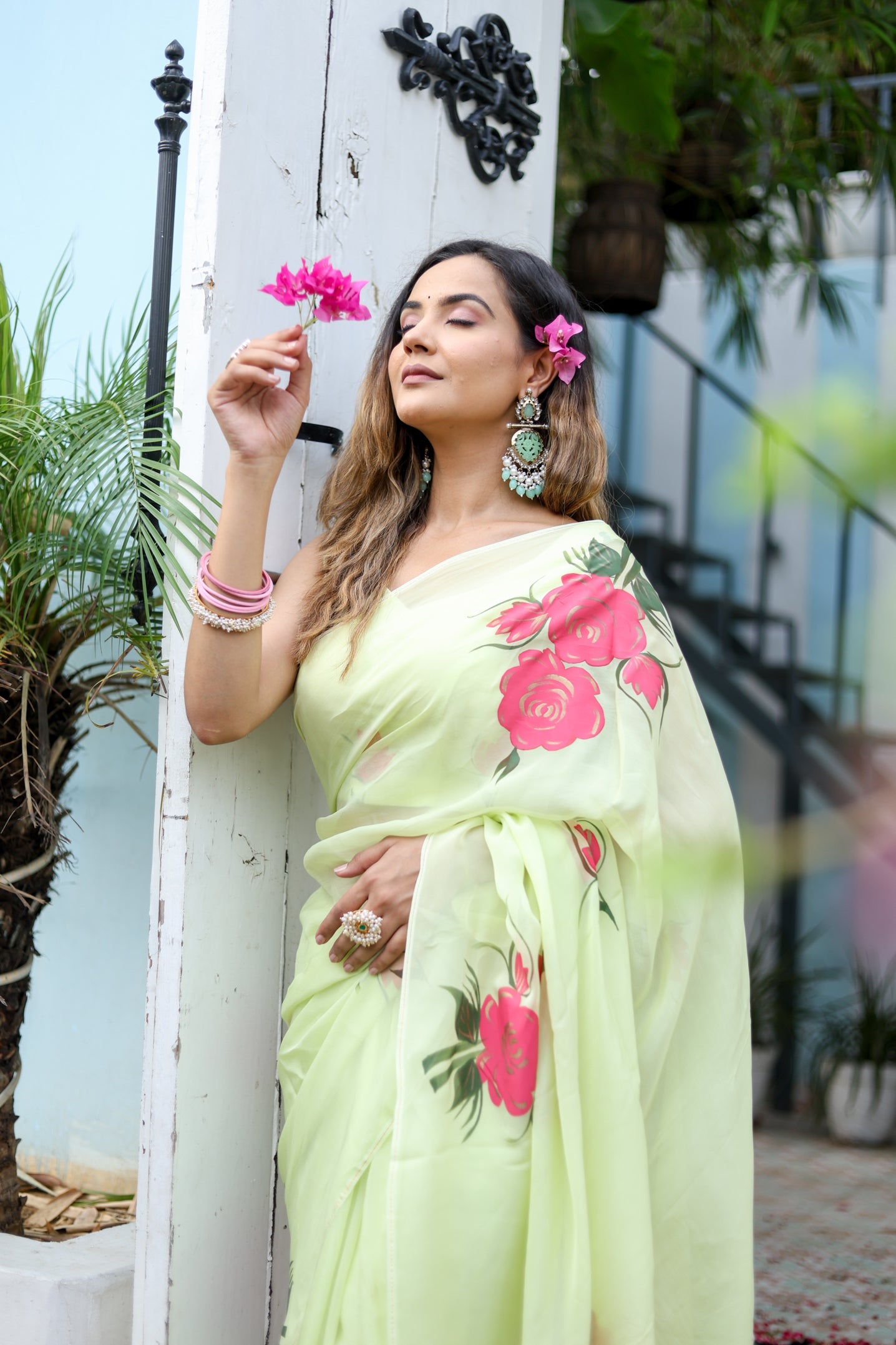 Model wearing a lightweight pastel saree with floral print, styled with accessories and flowers in hair