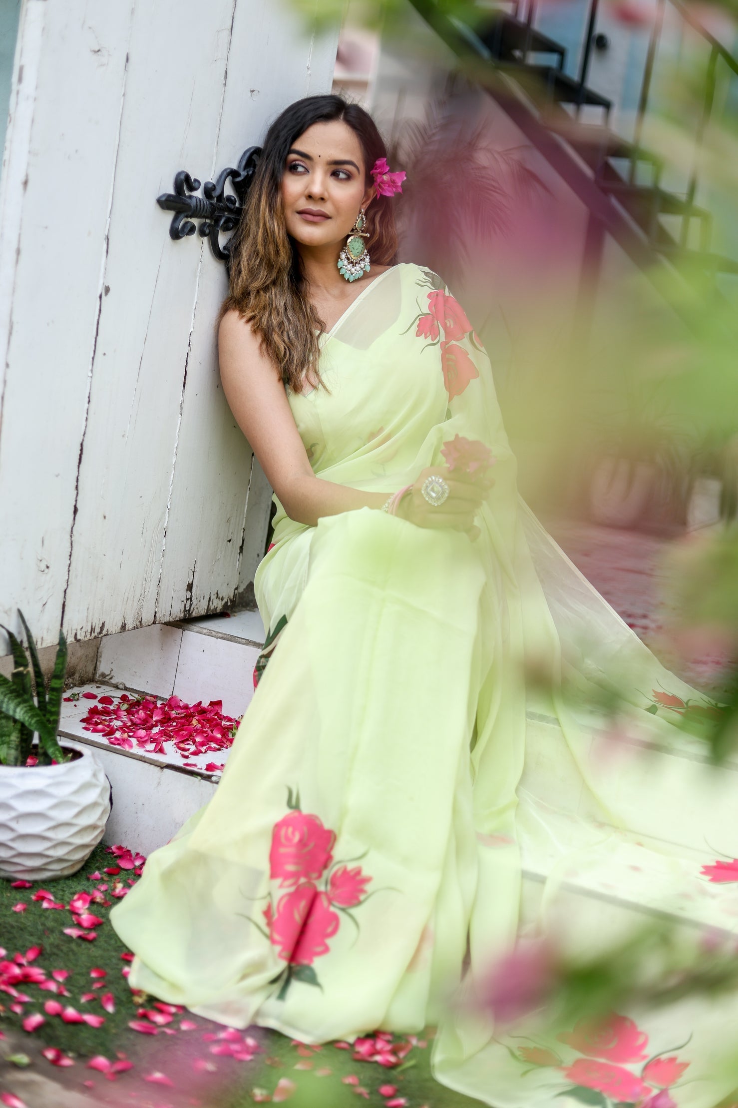 Model wearing a lightweight pastel saree with floral print, styled elegantly with floral accessories