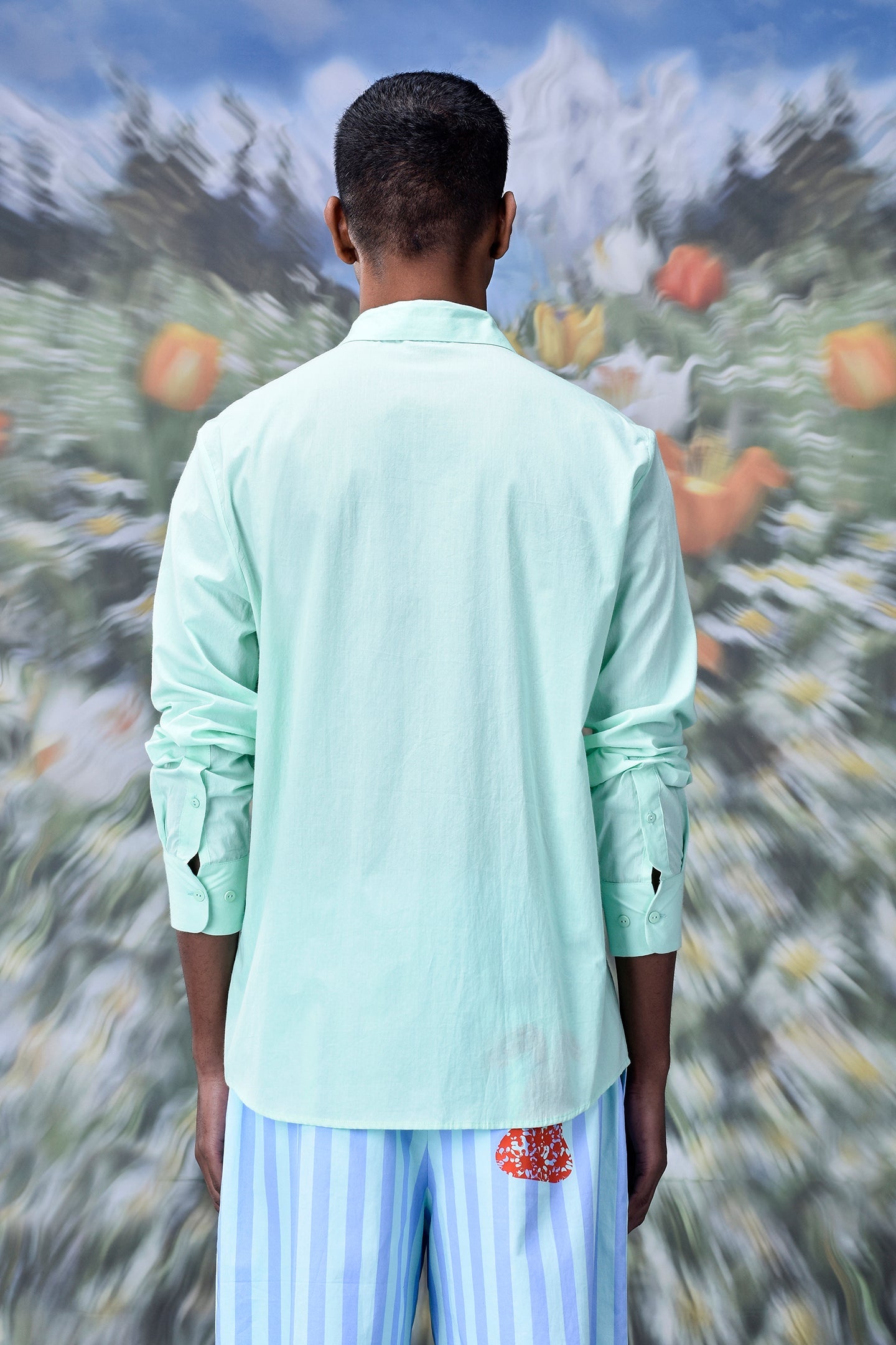 Male model back view wearing mint malmal regular fit formal shirt with long sleeves and casual striped pants
