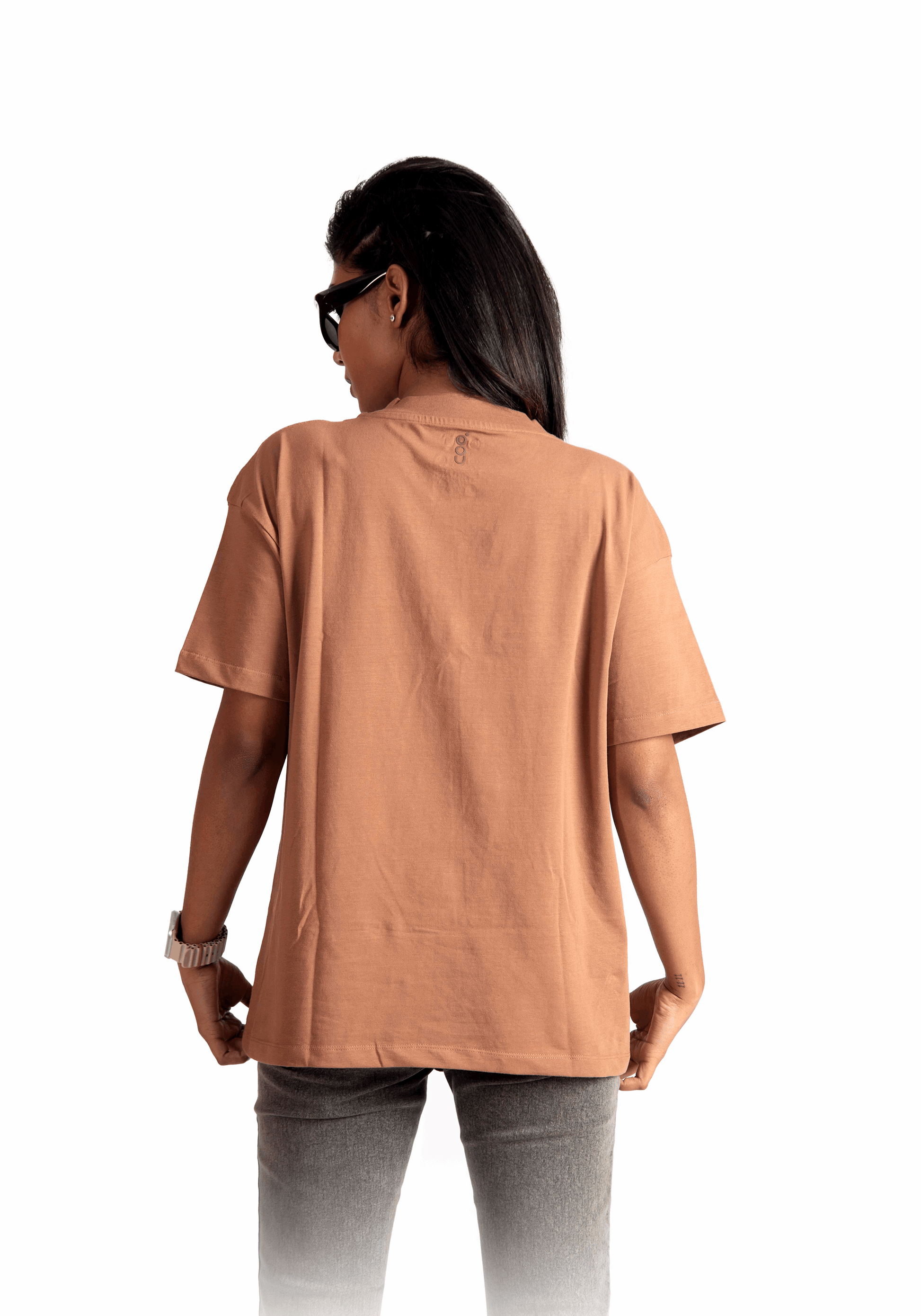 Back view of a woman wearing a Mocha Brown oversized t-shirt by Stylera paired with gray jeans